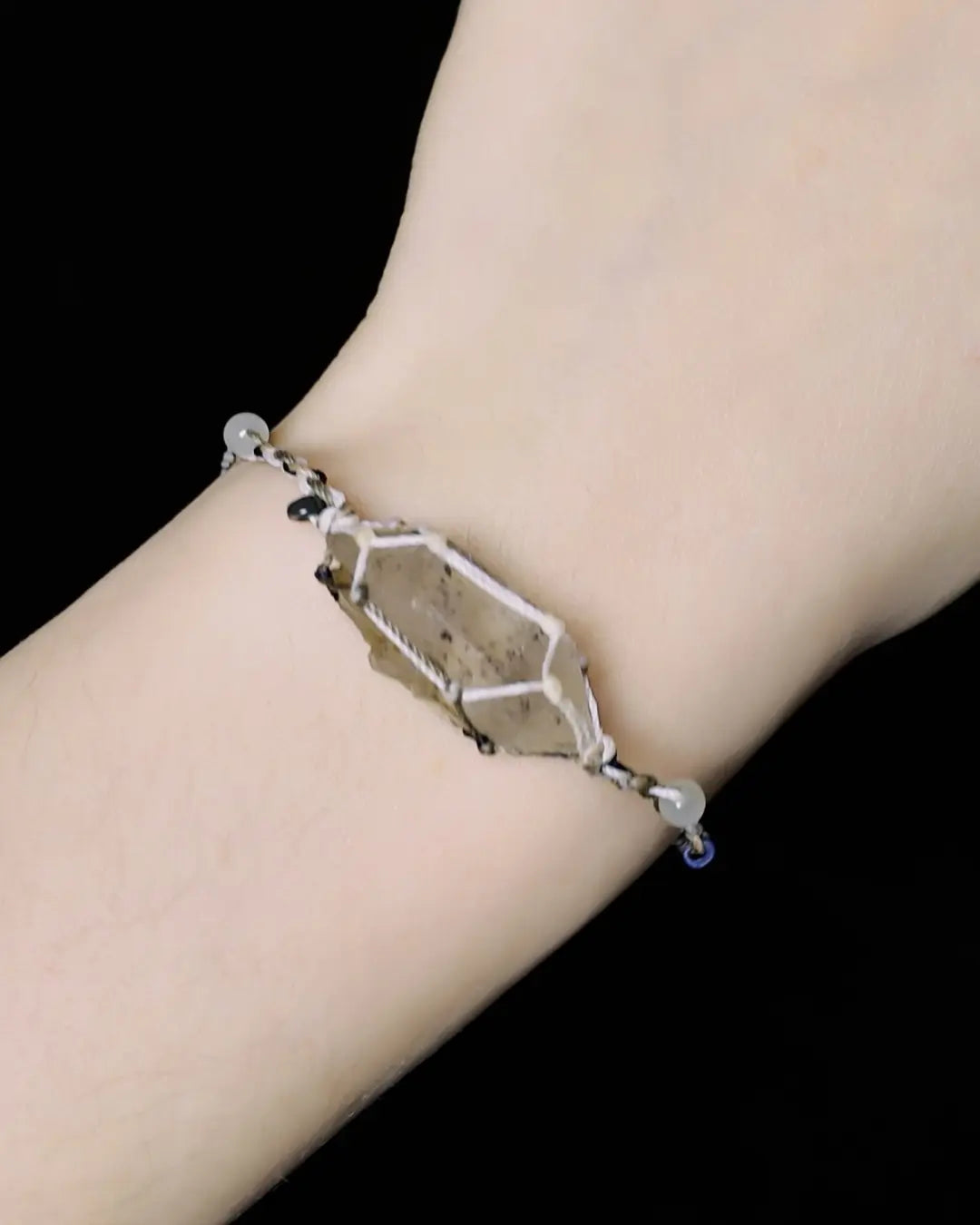 The Alchemist #09 Himalayan smoky quartz bracelet by à la luck — worn on the wrist showing the raw smoky quartz focal in macrame waxed thread with white jade and glass bead accents on the adjustable cord.