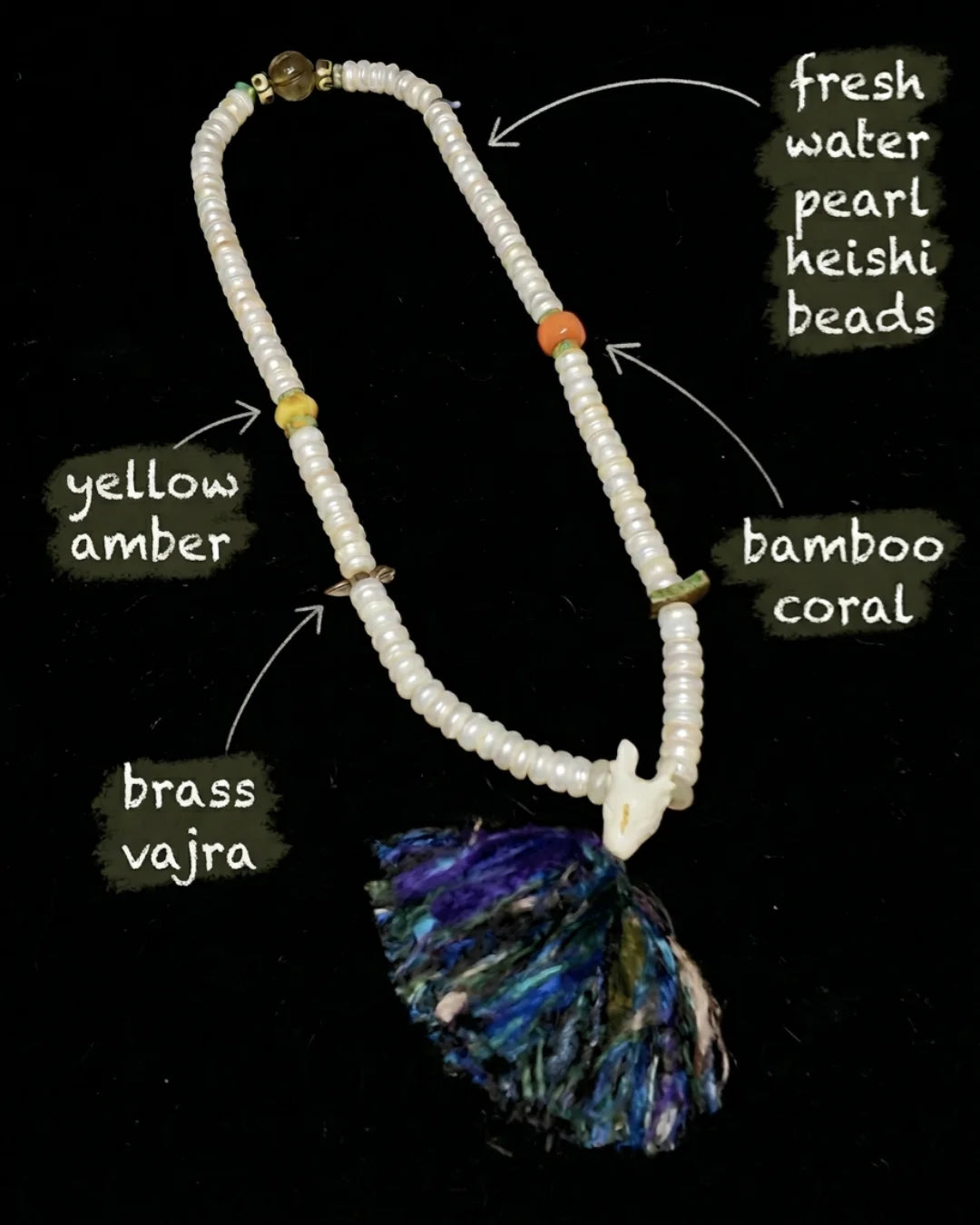 Hand-knotted mala necklace with fresh water pearl beads, bamboo coral, yellow amber, brass vajra, and multicolored tassel on black background.