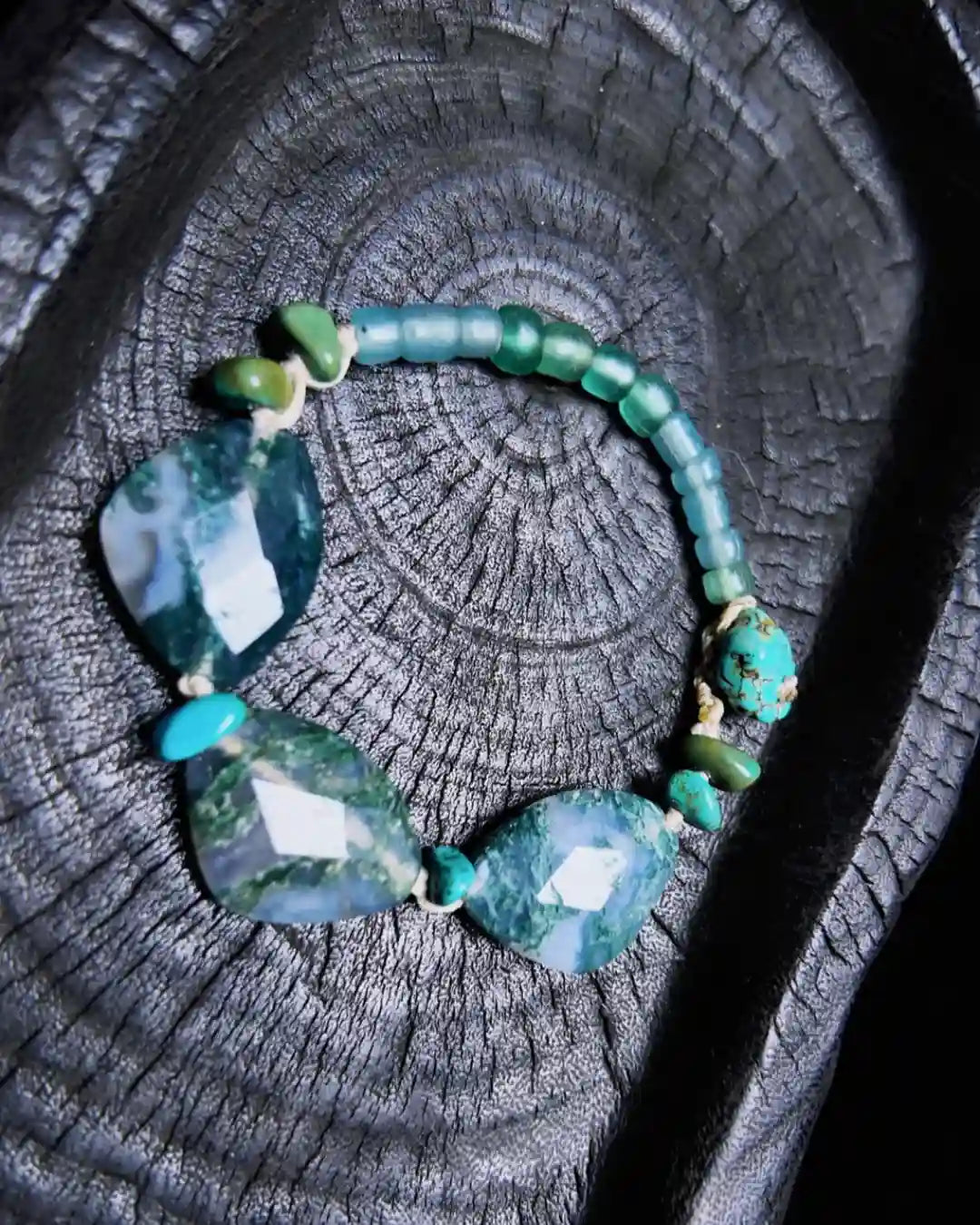 The Cultivator #18 moss agate abundance bracelet shown flat on charred wood — full edition-of-one bracelet by à la luck