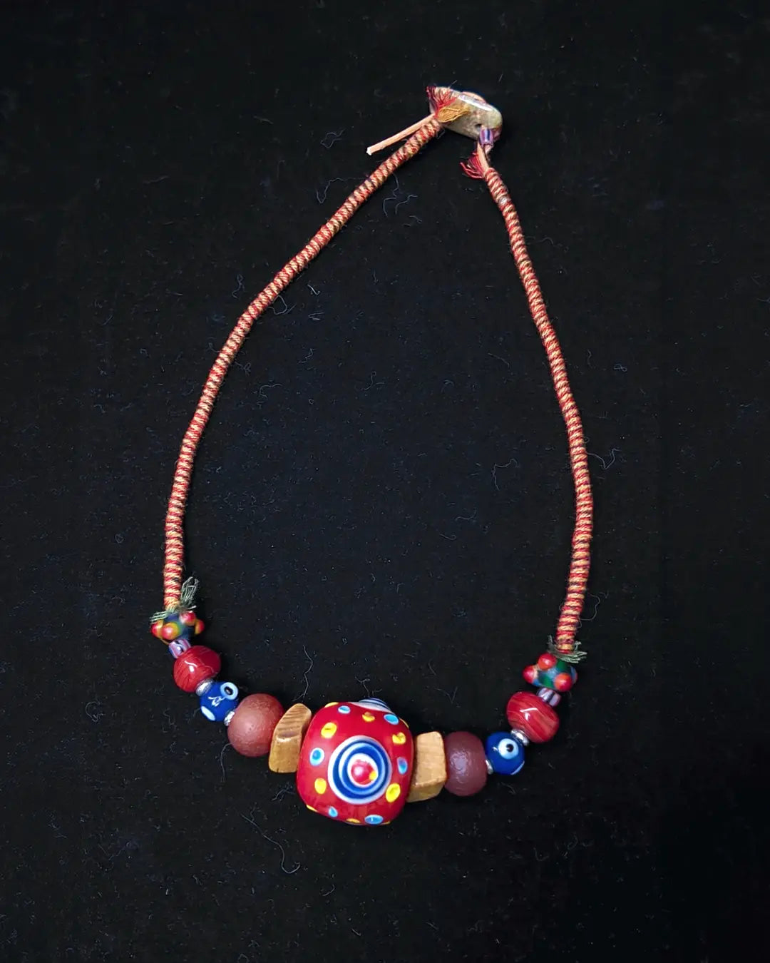 The Aegis #30 dragonfly eye protection necklace, full flat lay on dark surface showing complete bead arrangement and leather-cotton cord