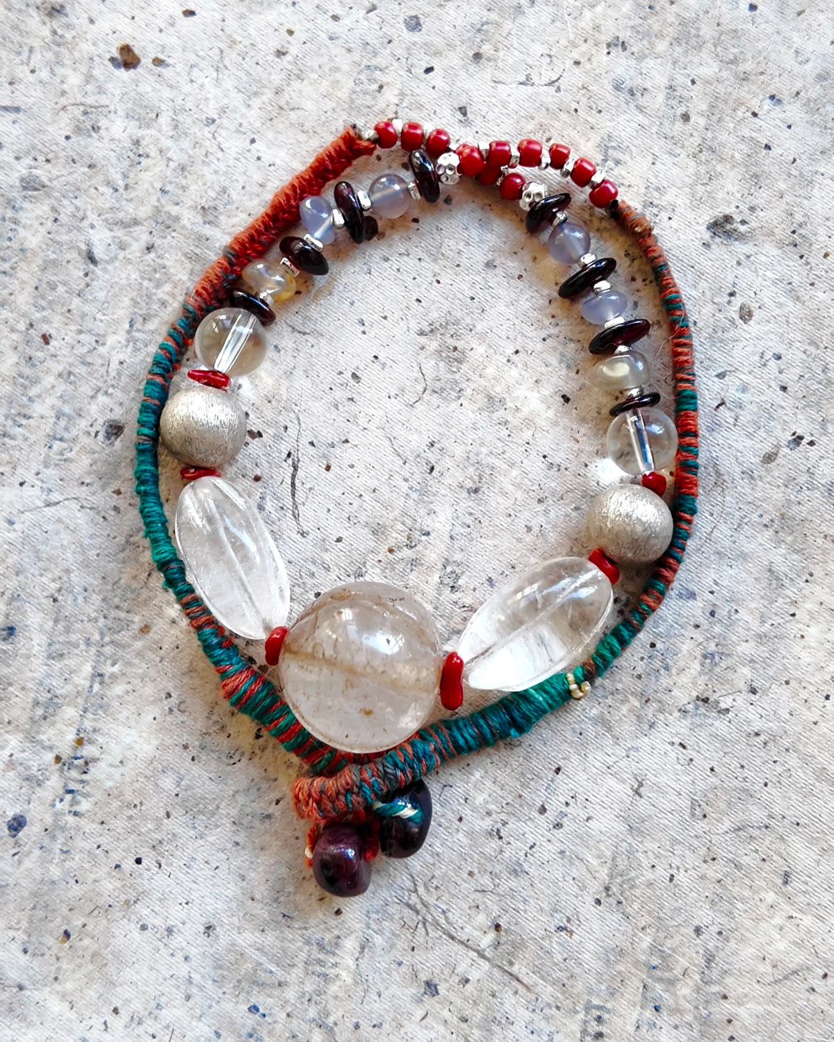 Coiled necklace showing the bead arrangement, wrapped cord and garnet finishing stones