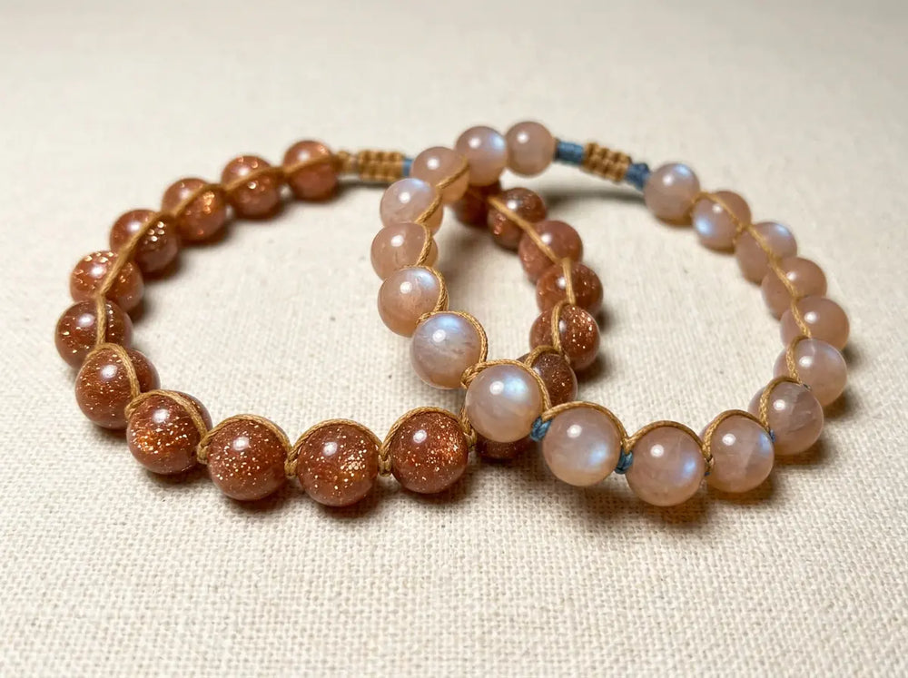 Sunstone bracelet next to orange moonstone bracelet under matching warm light, showing aventurescence glitter on the left and adularescence soft sheen on the right — feldspar family identification comparison.