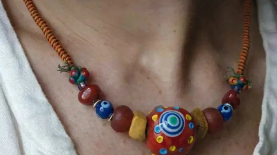 The Aegis #30 worn at the collarbone with a 33 mm Nepali estate dragonfly-eye bead, red Agate, glass eye beads, yak bone, and wrapped cord
