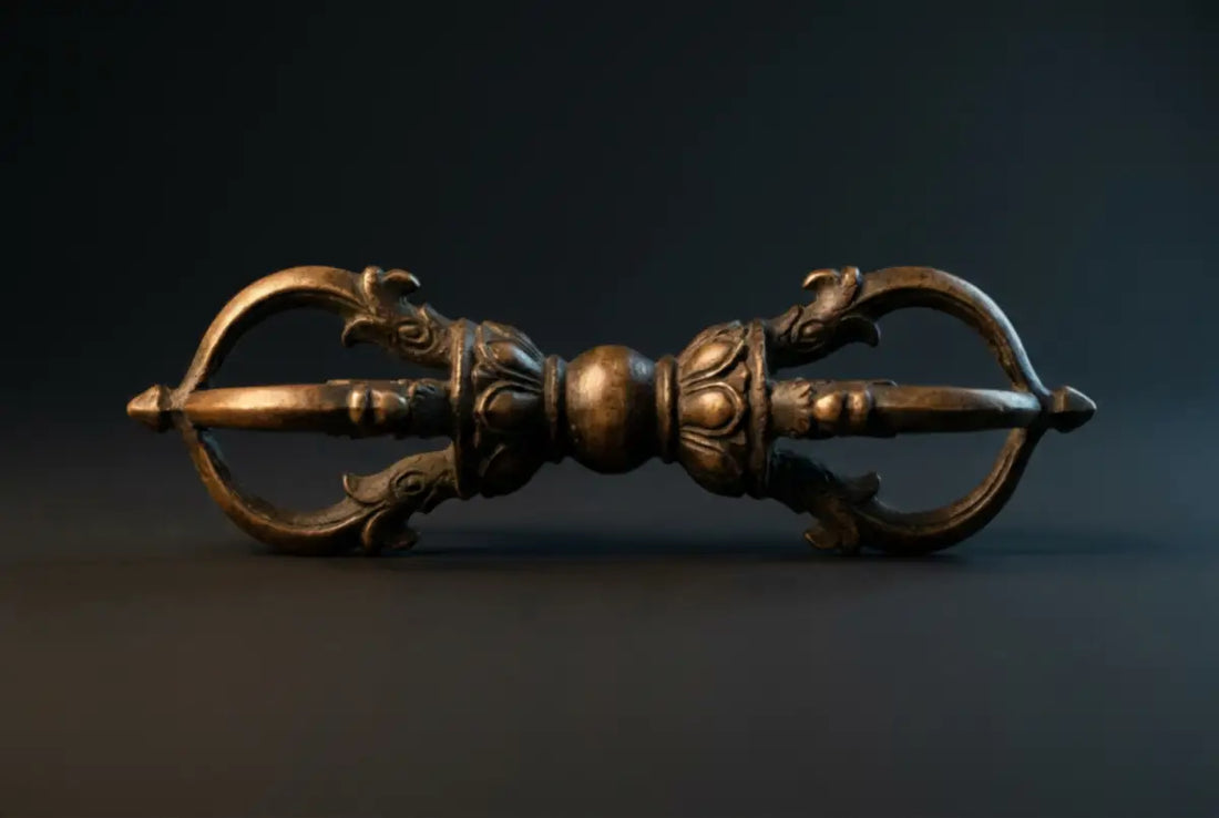 Antique five-pronged Tibetan Buddhist vajra (dorje) ritual scepter in aged bronze, perfectly symmetrical, prongs curving inward to a closed point on a dark slate ground — the adamantine emblem of the Vajrayana path.