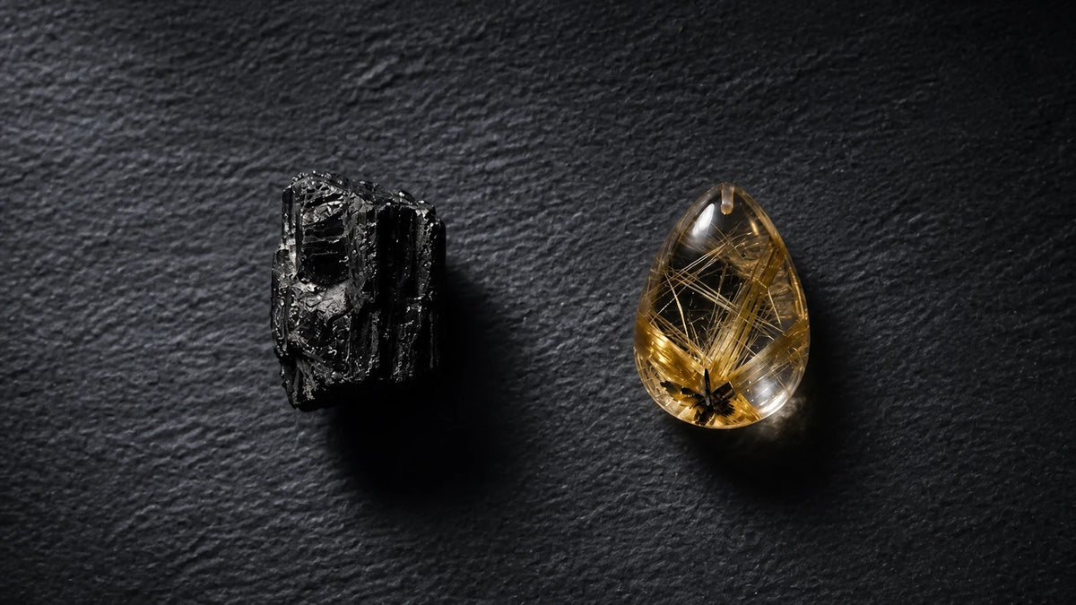 Conceptual still life of a dark raw crystal and a golden needle-included cabochon under the same soft light, representing the overlap between amulet and talisman.