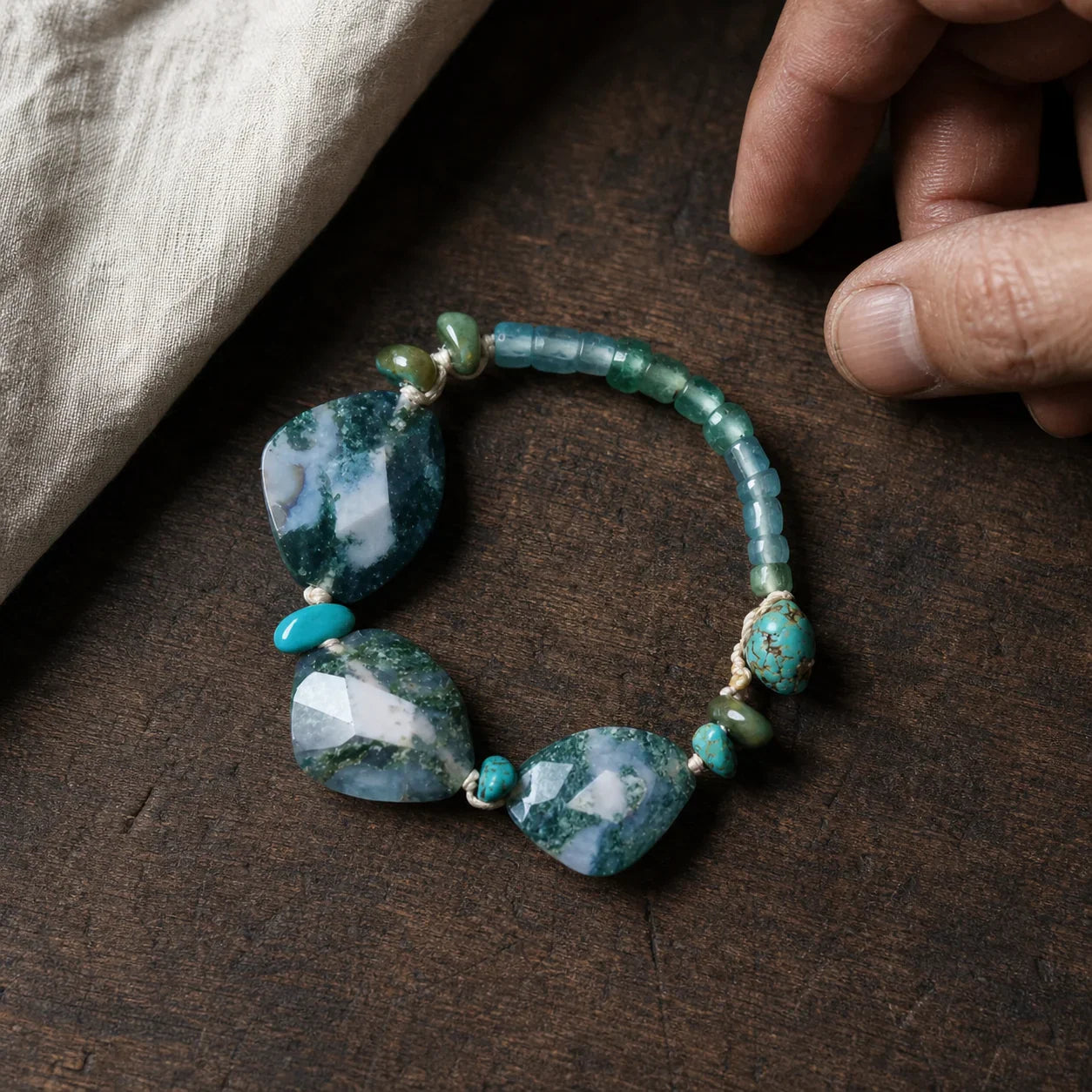 Moss agate and turquoise abundance bracelet on a walnut workbench