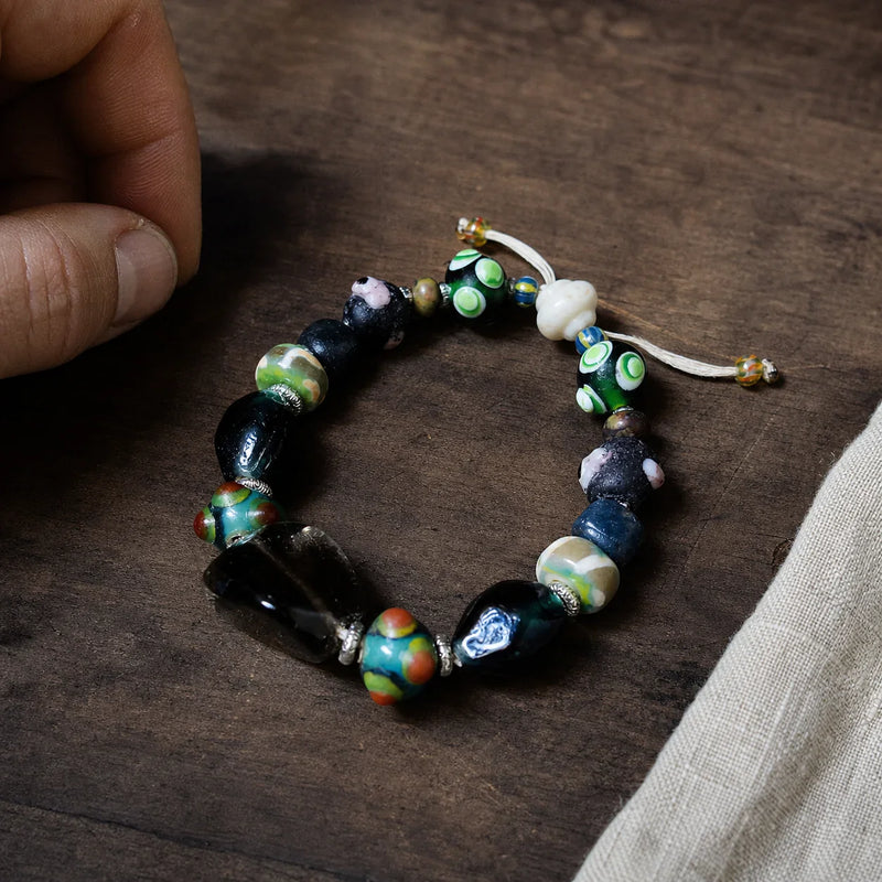 Protection bracelet with smoky quartz and glass eye beads on a walnut workbench