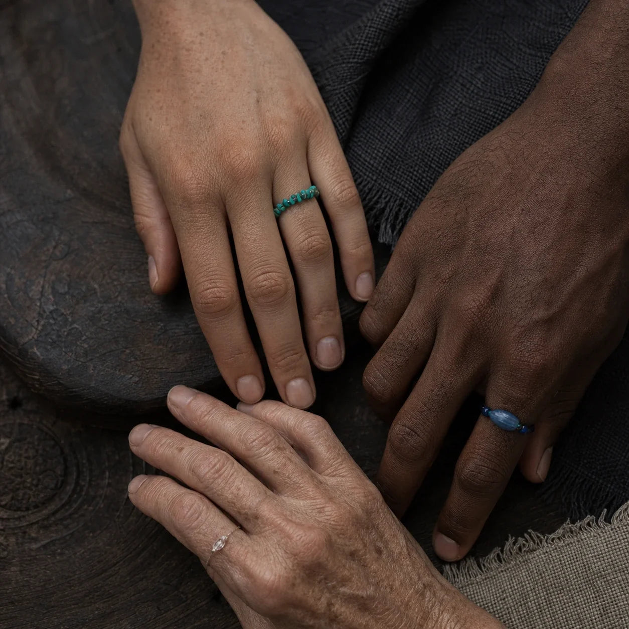 Three hands of different ages and skin tones wearing handmade raw-stone cord rings by à la luck