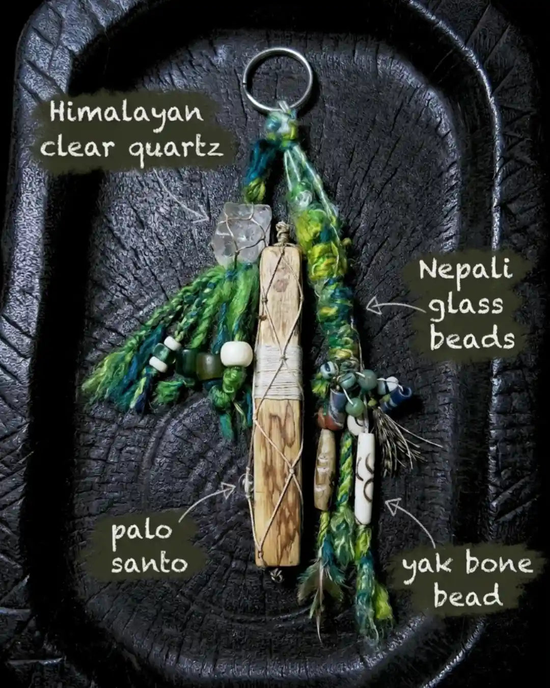Material detail for The Sanctuary #02 — labelled Himalayan clear quartz, Nepali glass beads, palo santo, and yak bone bead components of the hand-knotted bag charm.