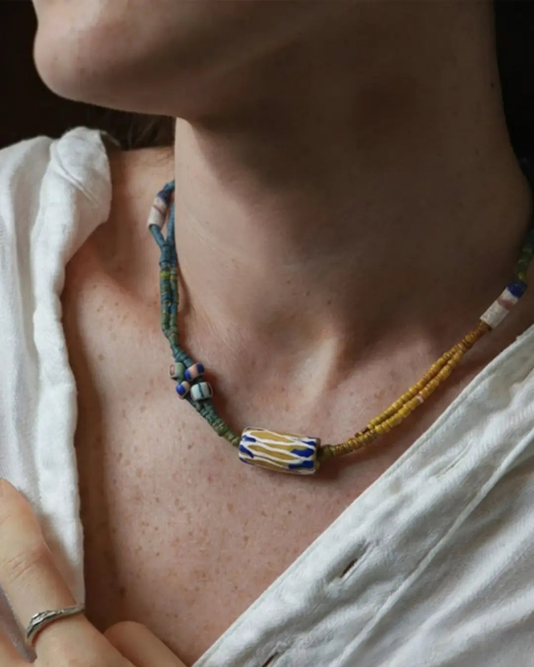 The Nomad #05 African trade bead wrap and choker by à la luck — worn at the neckline showing the African trade bead focal and the full multicolor plant-dyed cotton thread construction as a choker.