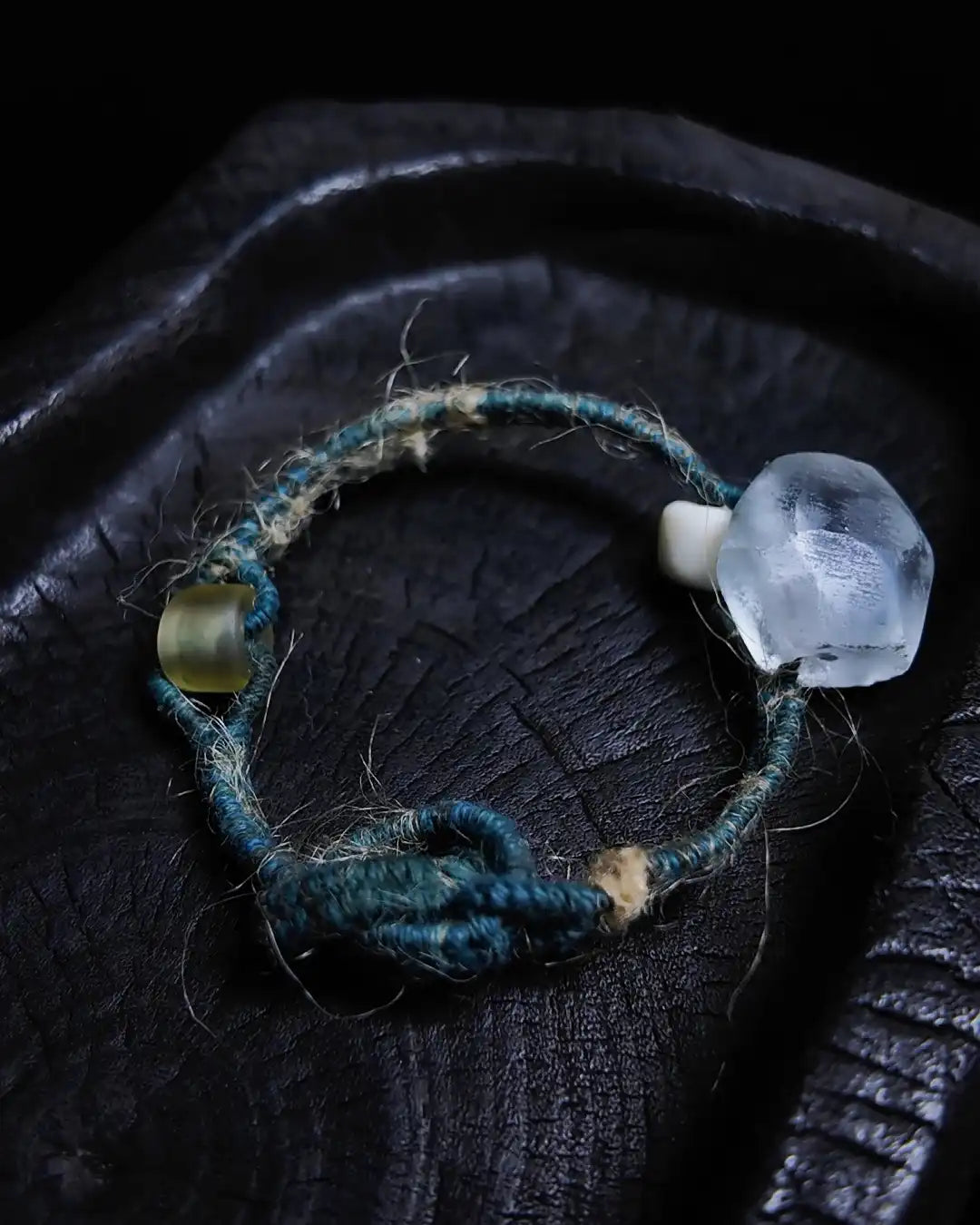 The Zen #08 patina glass bead energy bracelet shown flat on charred wood — full edition-of-one piece showing the Himalayan weathered glass bead, bodhi bead, and glass bead on plant-dyed cotton thread and hemp cord.