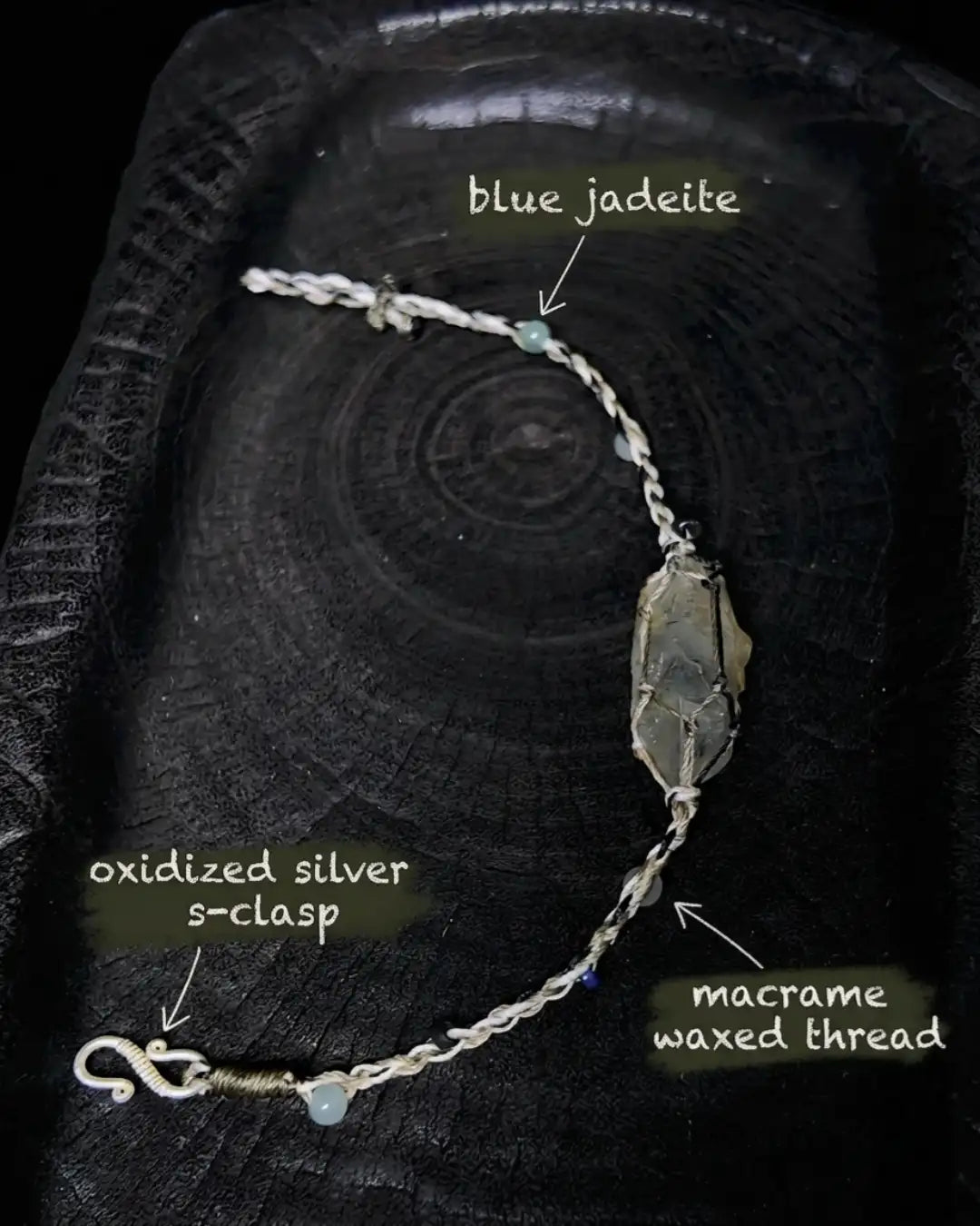 Material map for The Alchemist #09 — labelled blue jadeite accent bead, oxidized silver s-clasp, and macrame waxed thread used in the hand-knotted bracelet construction.
