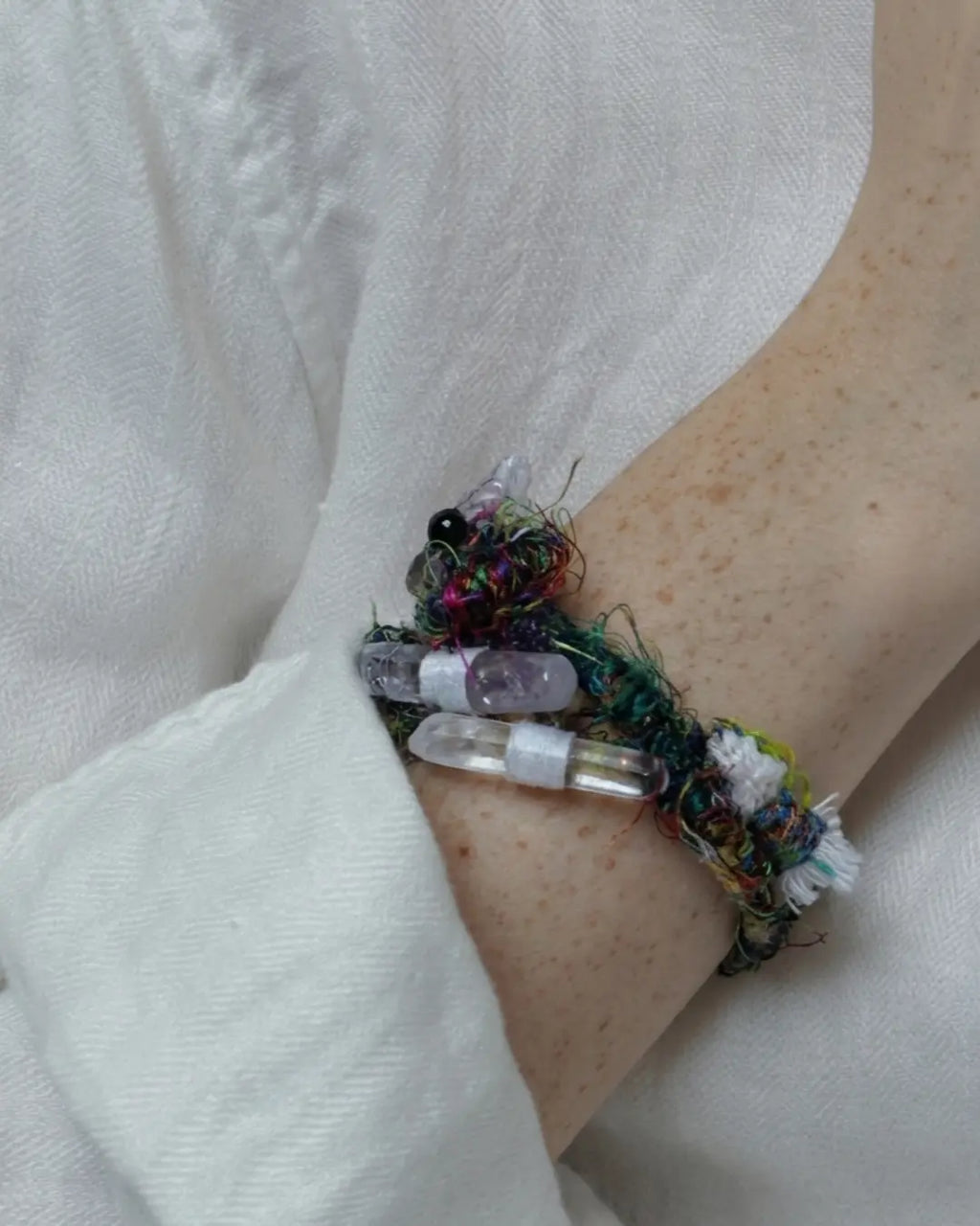 The Primal #11 Himalayan clear quartz piece by à la luck — worn as a wrap bracelet on the wrist showing the quartz points and Nepali banana silk yarn in the multi-loop configuration.