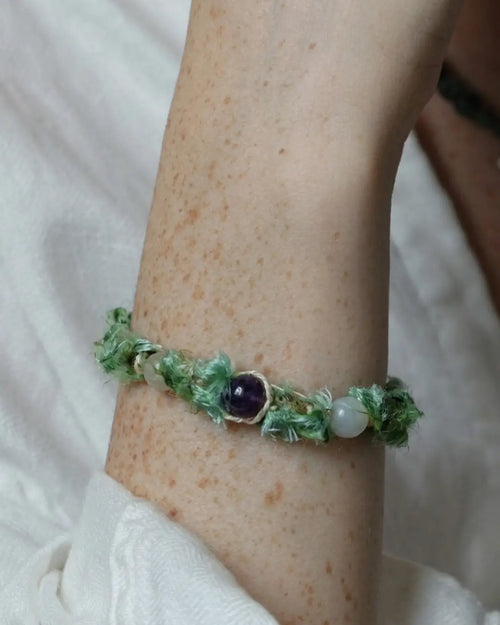 The Oasis #13 hetian jade bracelet by à la luck — worn on the wrist showing the hetian white jade and hetian green jade beads on green Nepali banana silk yarn with hemp cord adjustment.