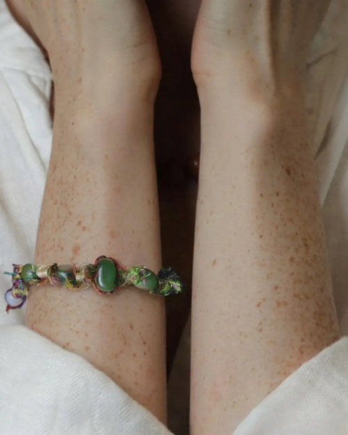 The Gaia #14 Hetian jade multi-stone bracelet by à la luck — worn on the wrist showing the Hetian green jade beads on multicolor Nepali banana silk yarn and hemp cord with oxidized brass bead accent.