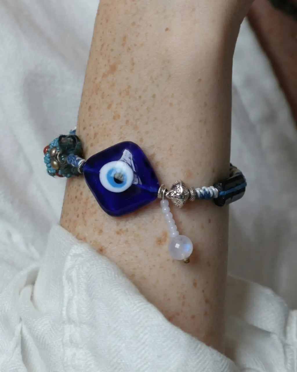The Sentinel #15 evil eye and black tourmaline talisman bracelet by à la luck — worn on the wrist showing the square evil eye focal and hanging moonstone drop