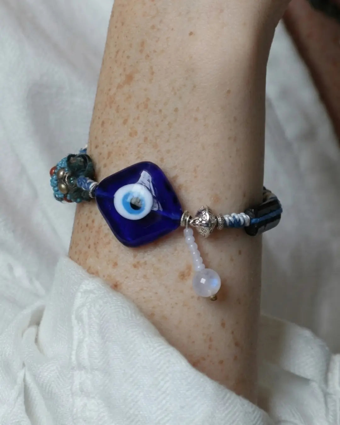 The Sentinel #15 evil eye and black tourmaline talisman bracelet by à la luck — worn on the wrist showing the square evil eye focal and hanging moonstone drop