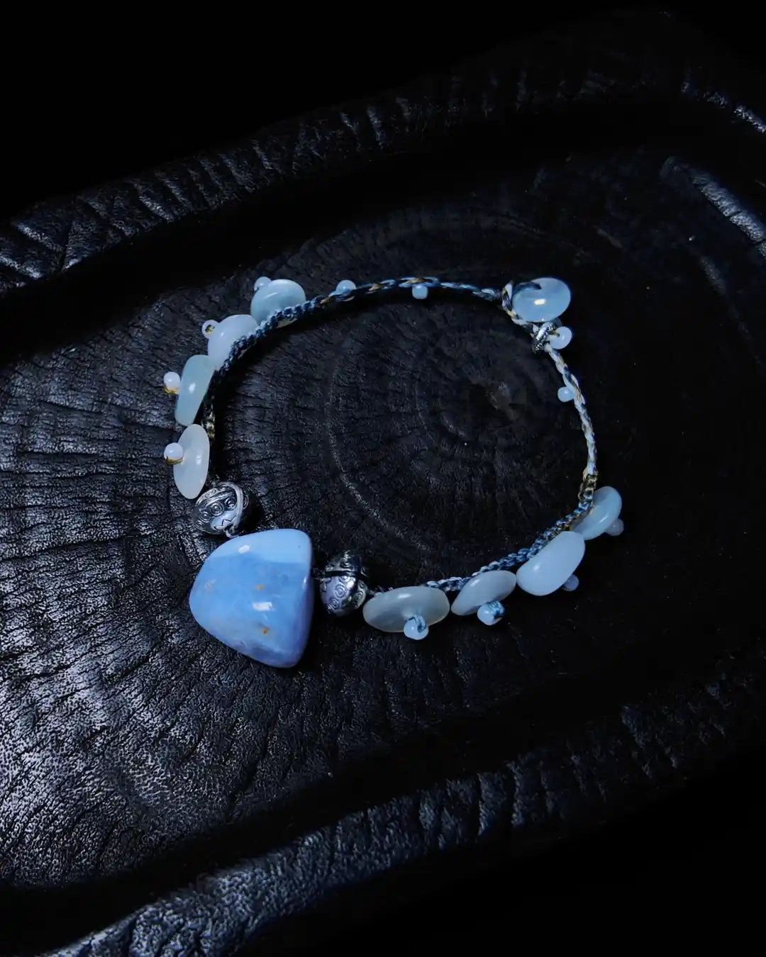 The Oracle #17 blue lace agate and moonstone bracelet shown flat on charred wood — full edition-of-one bracelet by à la luck