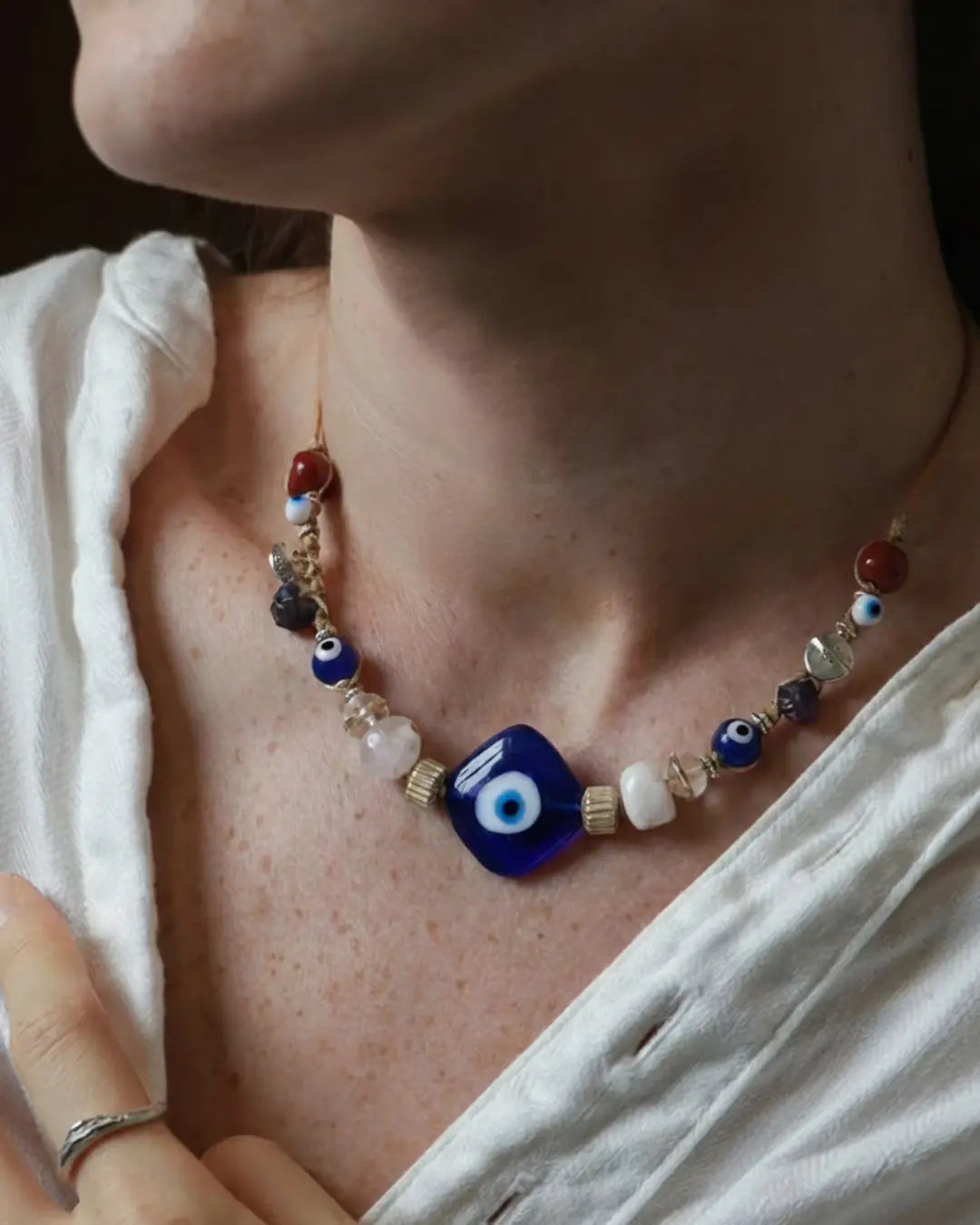 The Seer #19 evil eye and raw sapphire protection necklace by à la luck — worn at the neckline showing the cobalt evil eye glass focal bead