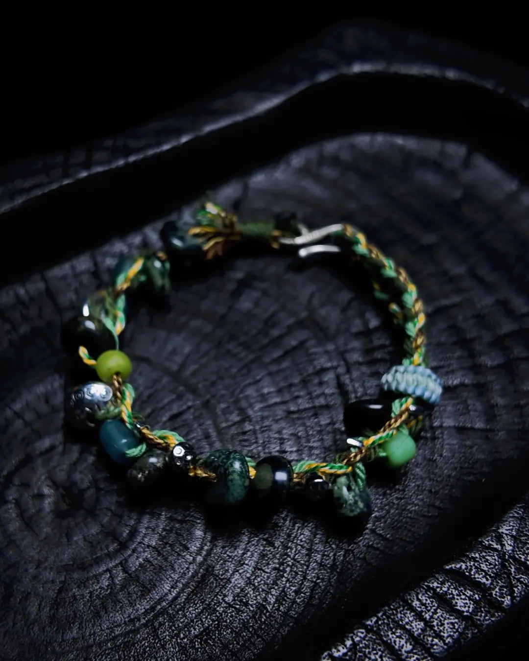 The Earthbound #20 rainforest jasper grounding bracelet shown flat on charred wood — full edition-of-one bracelet by à la luck