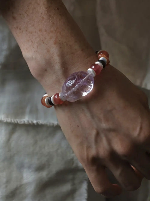 The Mystic #23 amethyst quartz bracelet worn on wrist, lifestyle right-angle shot on linen background