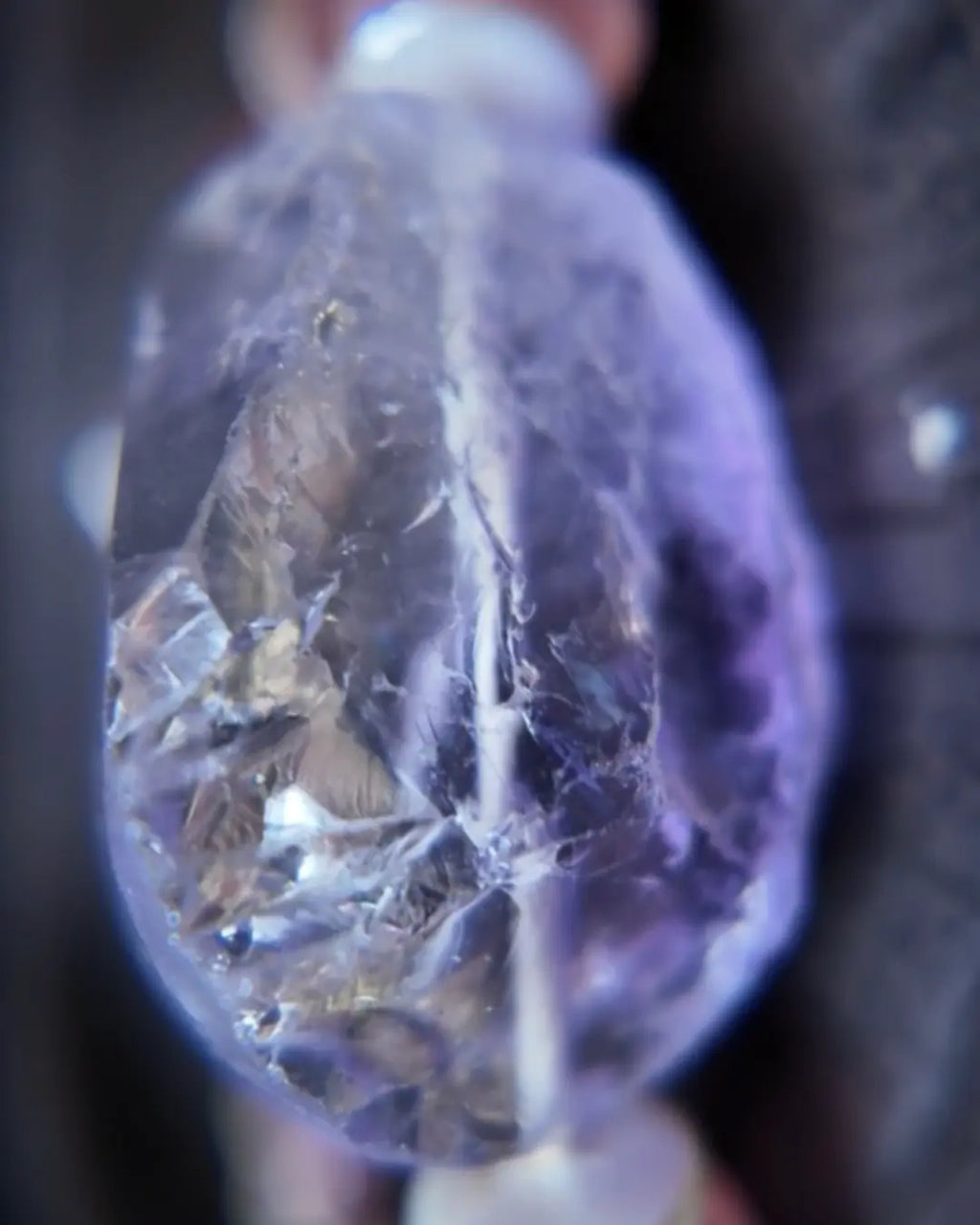 Extreme close-up of polished Himalayan amethyst quartz focal stone, showing rainbow inclusions and internal phantom layers within translucent lavender quartz