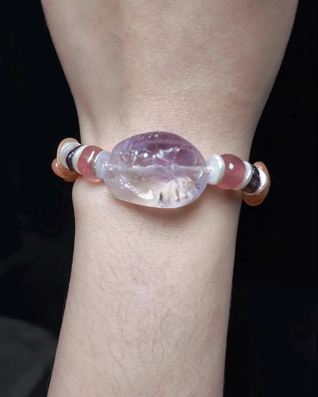 The Mystic #23 amethyst quartz bracelet worn on wrist, front-angle lifestyle shot showing complete bead stack