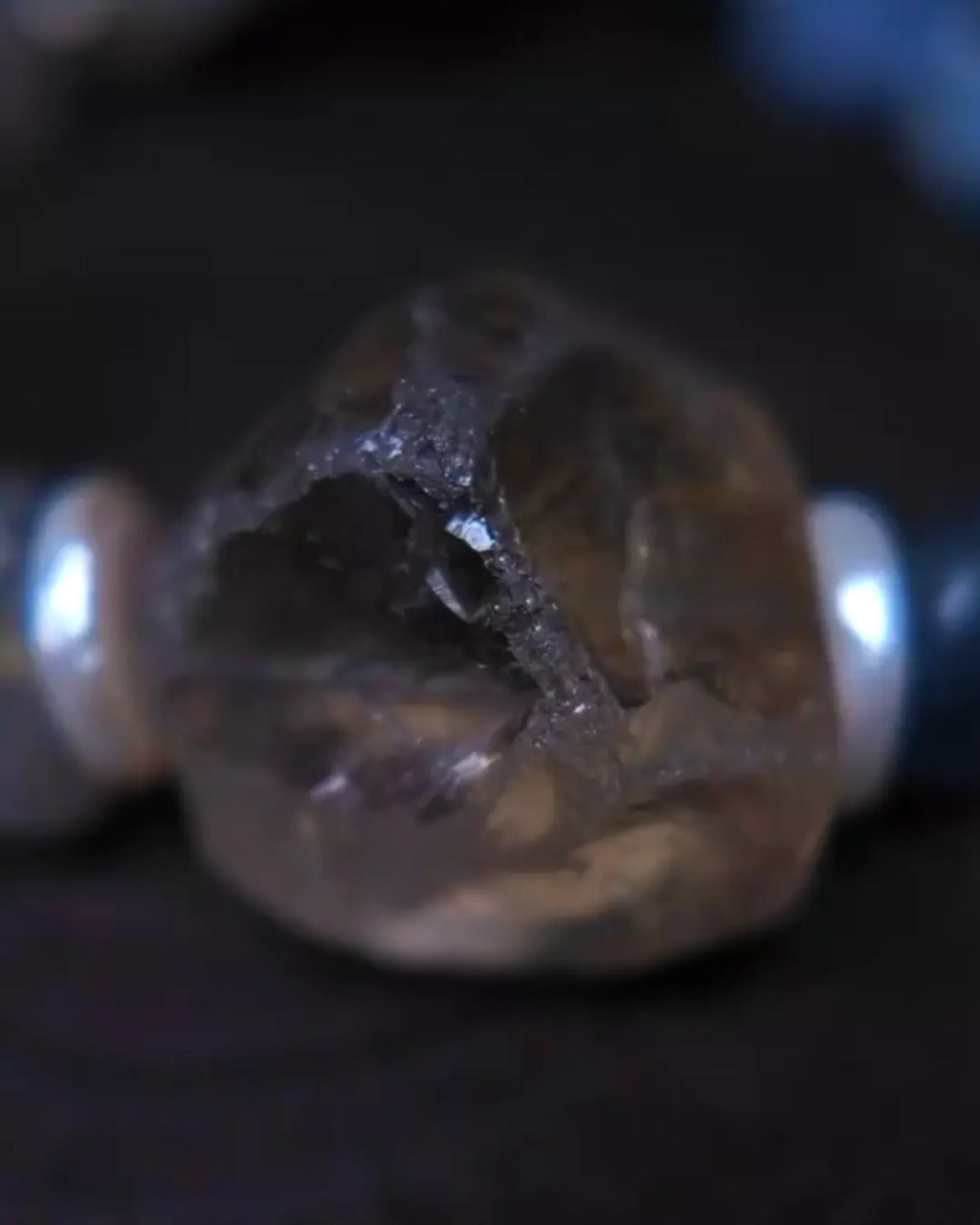 Extreme macro of polished smoky quartz focal stone revealing internal phantom inclusion landscape — dark angular cave-like fracture within translucent smoky body
