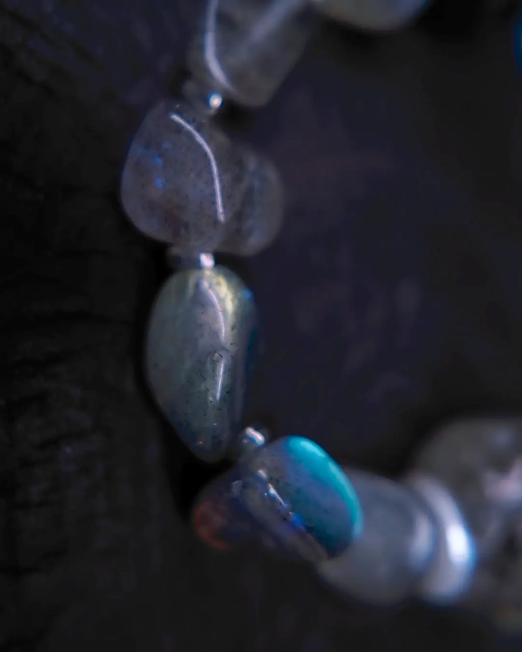 Macro detail of labradorite tumbled stones revealing characteristic blue-gold labradorescence flash within grey feldspar matrix