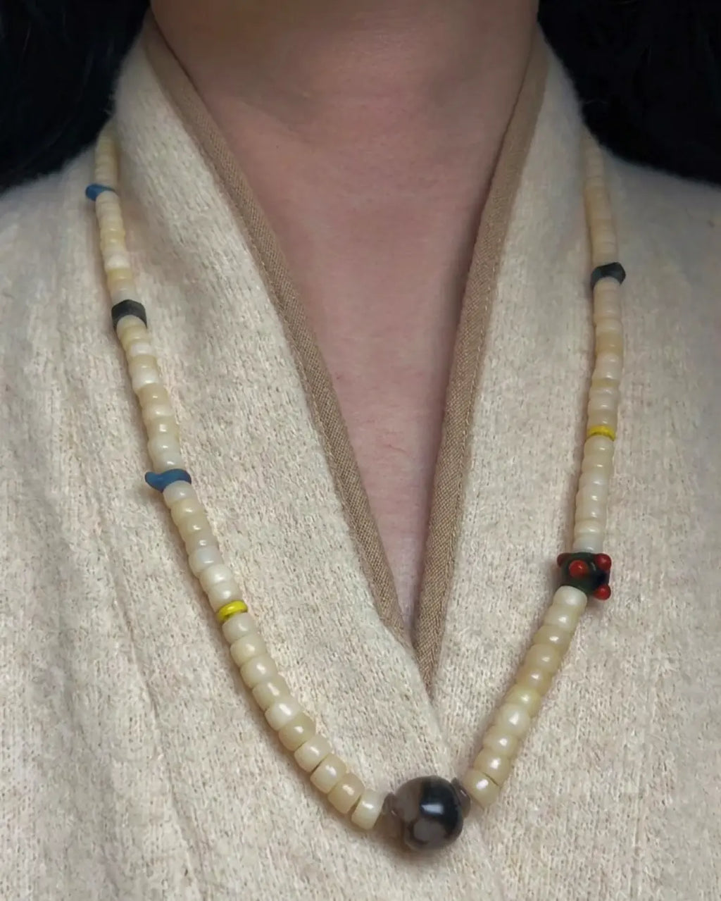 The Veil #28 necklace, full flat lay on dark wood surface showing complete bead arrangement