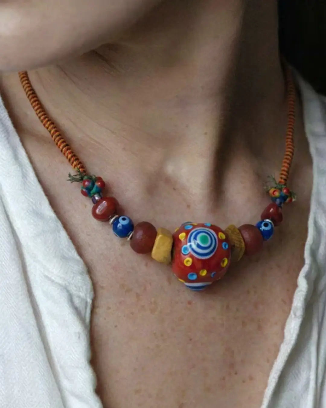 The Aegis #30 dragonfly eye protection necklace worn on neck, lifestyle shot showing 33mm dragonfly eye focal at collarbone