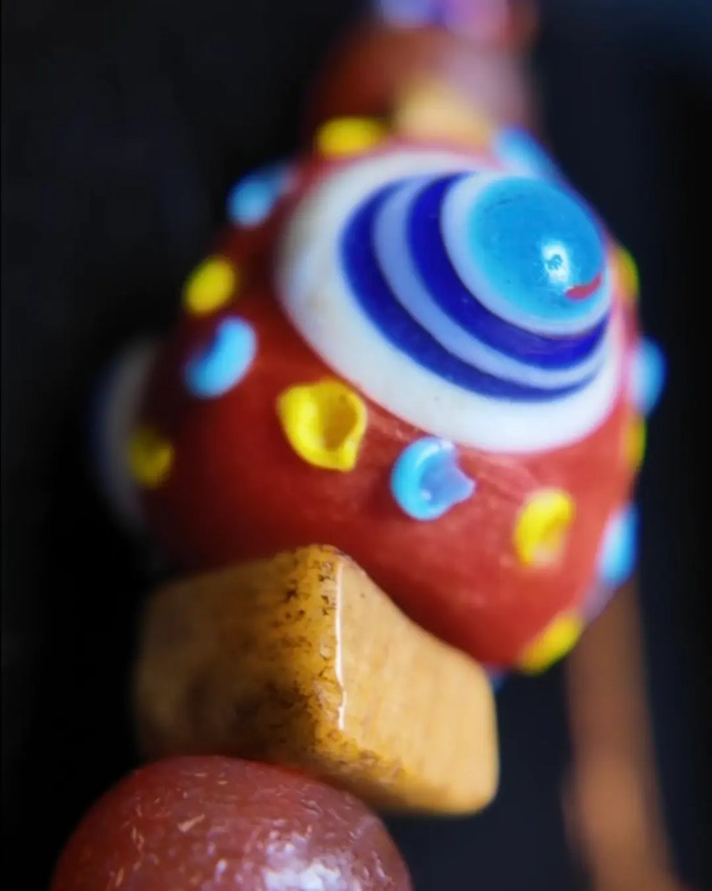 Macro detail of 33mm Nepali estate dragonfly eye focal bead — concentric-circle apotropaic eye motif in red glass
