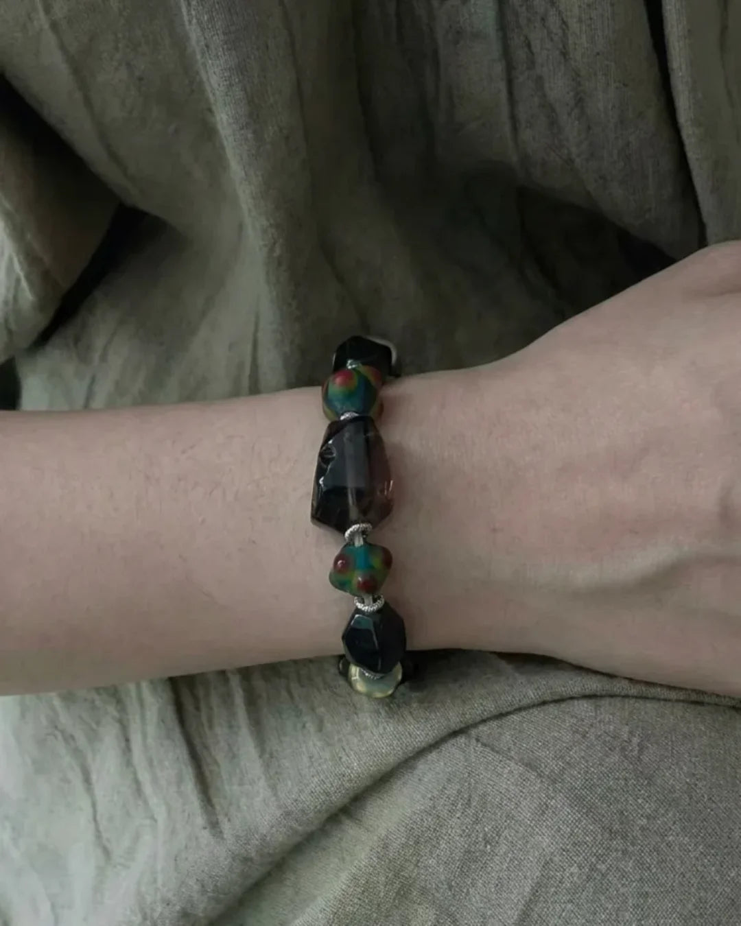 The Warden #32 smoky quartz and Tibetan dzi protection bracelet worn on wrist, lifestyle shot showing smoky quartz focal and colorful dragonfly eye glass beads