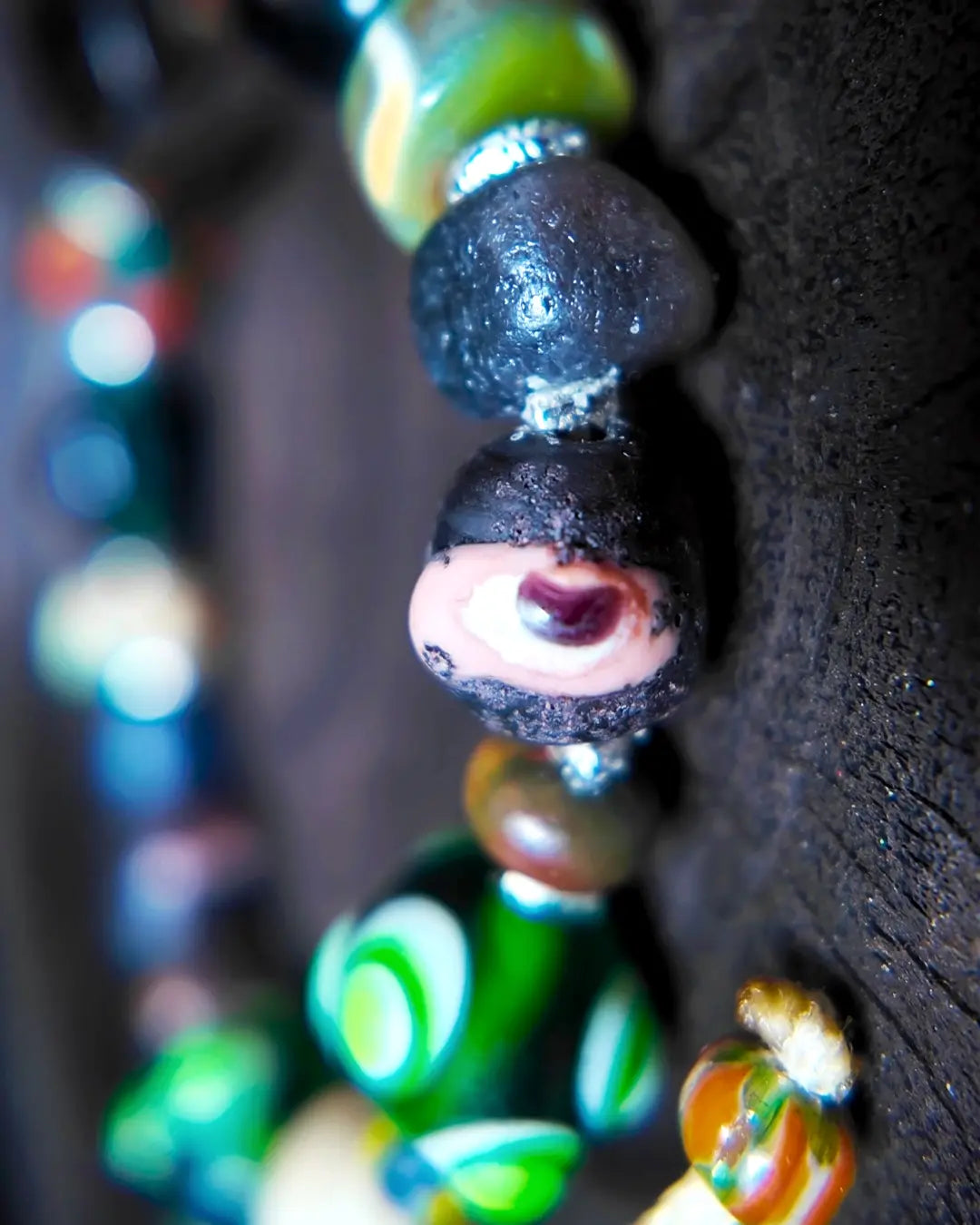 The Warden #32 smoky quartz and Tibetan dzi protection bracelet, detail view 7 — showing dragonfly eye, evil eye glass, raw sapphire, and red creek jasper accents