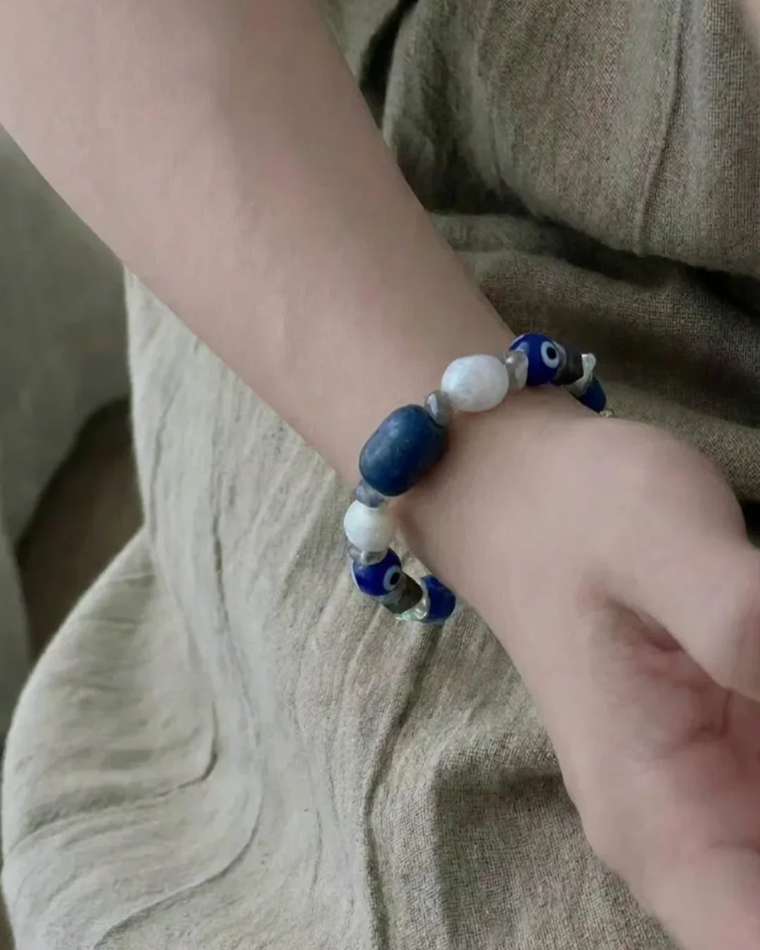The Augur #33 lapis lazuli and blue moonstone vision bracelet worn on wrist, lifestyle shot showing deep blue lapis focal and white blue moonstone beads