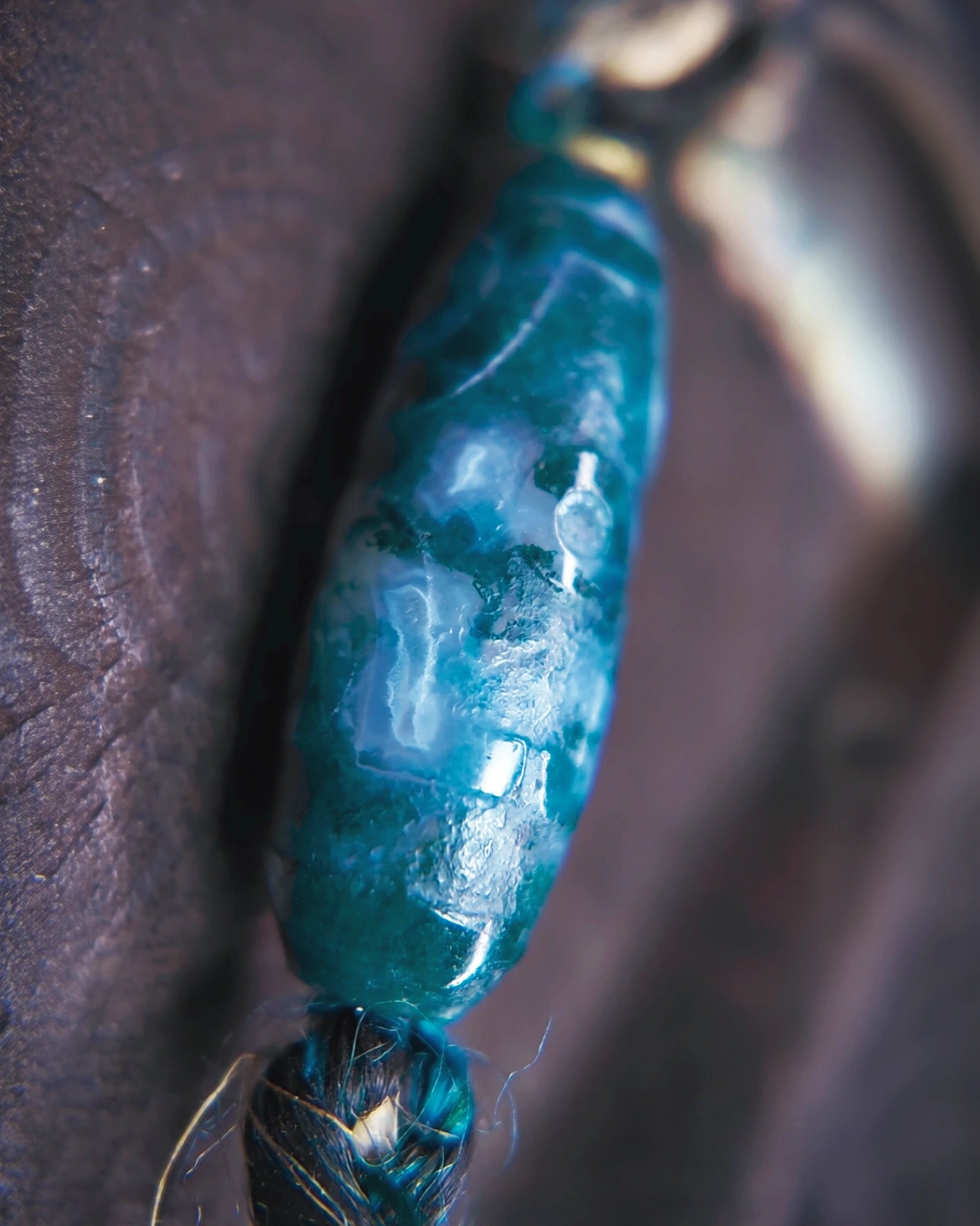 Angled macro view of the moss agate Dzi-form focal and wrapped cord