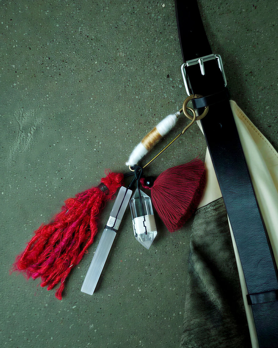 The Beacon #41 quartz and selenite talisman attached to a leather bag strap for scale