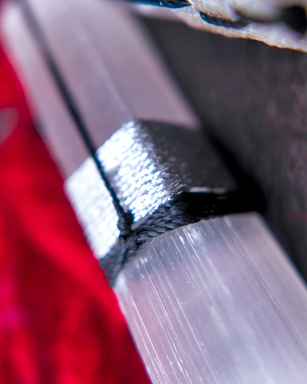 Waxed and iridescent synthetic thread securing the selenite point without glue