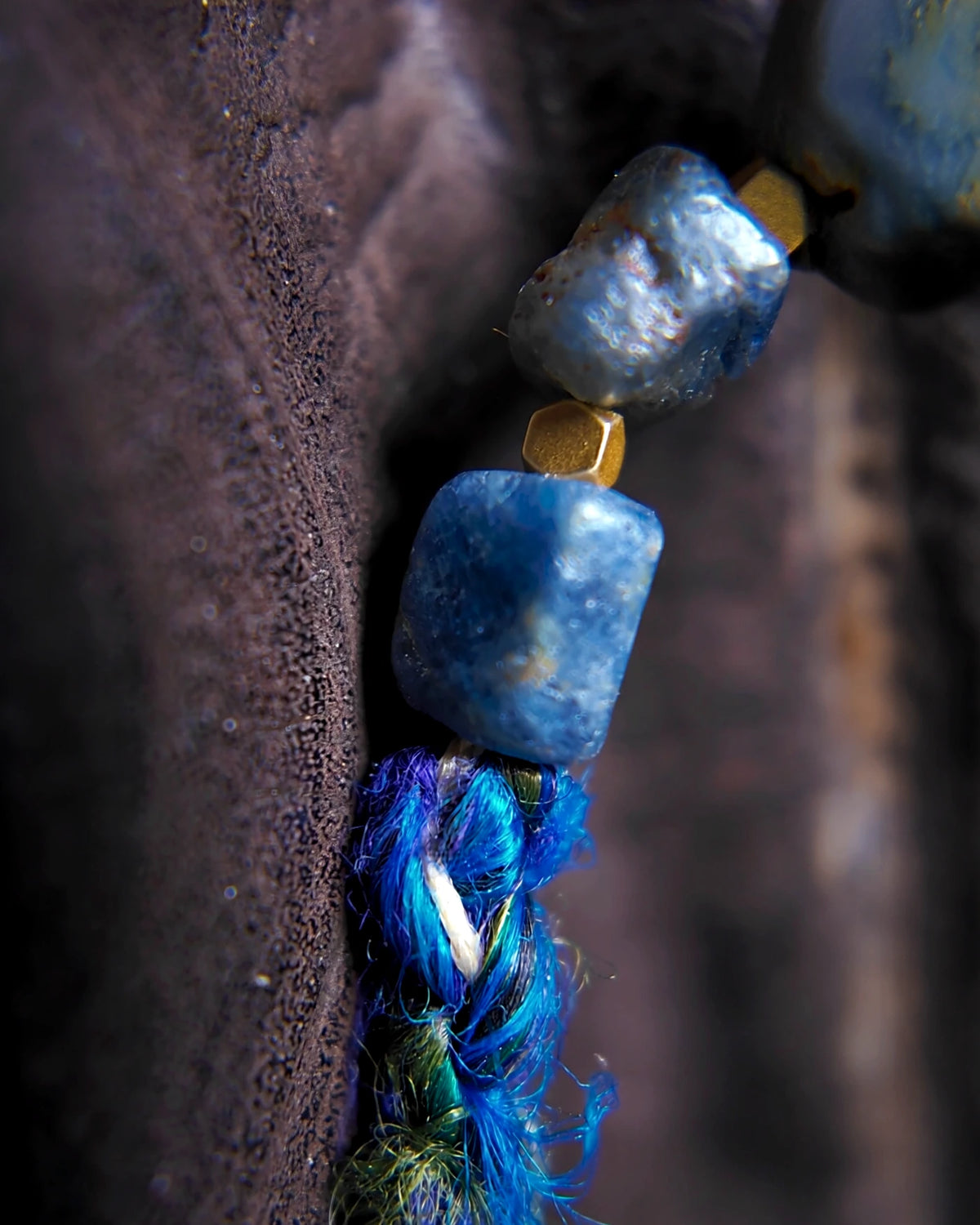 Raw sapphire stones, brass spacers and blue banana-silk yarn at the side of the necklace