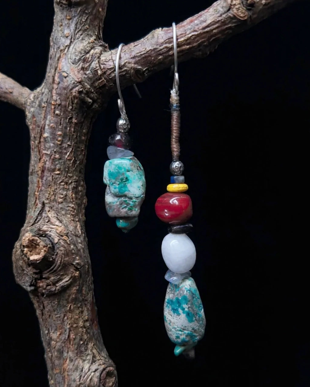 The Counterpoint #38 asymmetric turquoise earrings displayed together on a natural branch