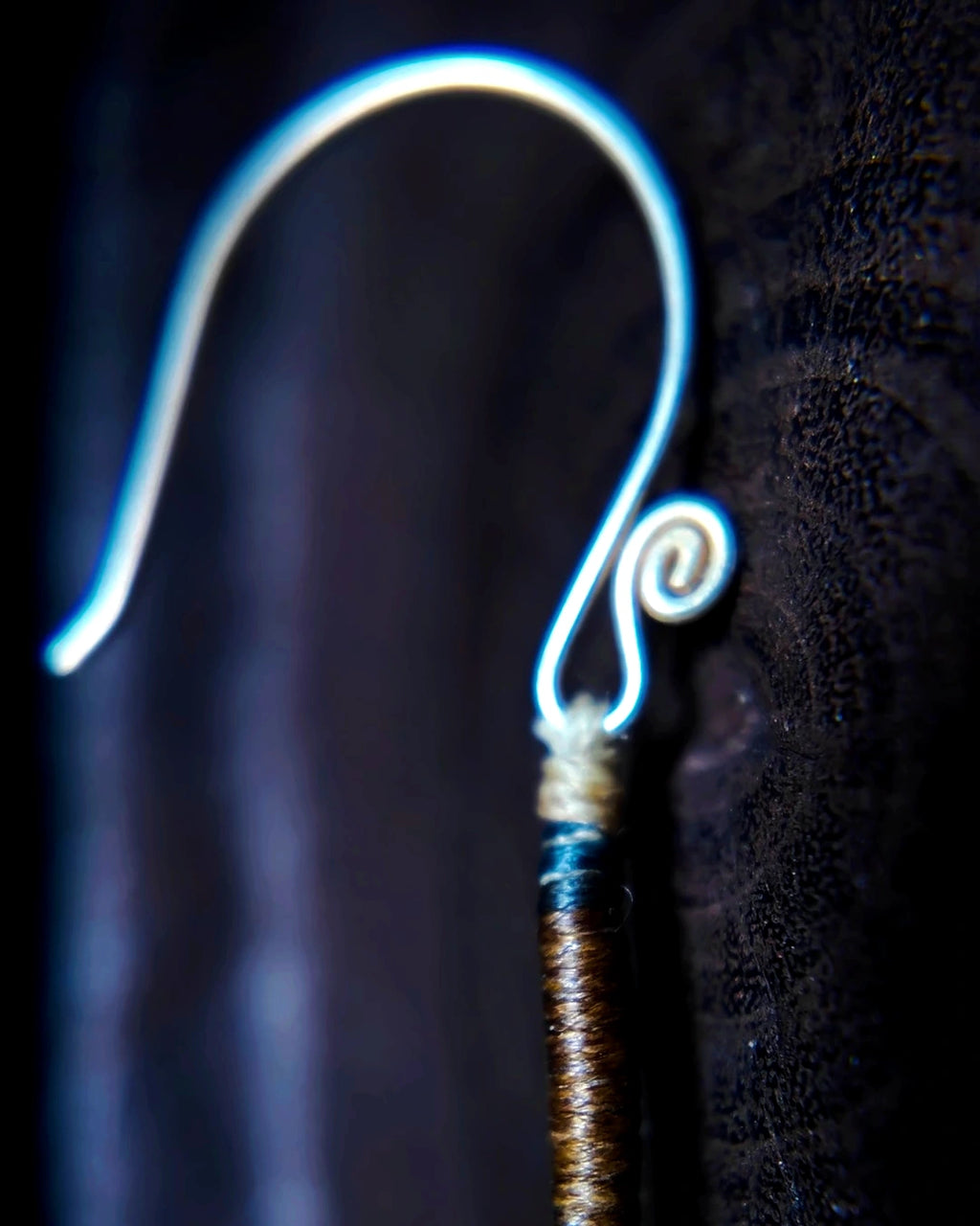 Macro detail of the waxed-thread construction and silver-plated copper ear hook