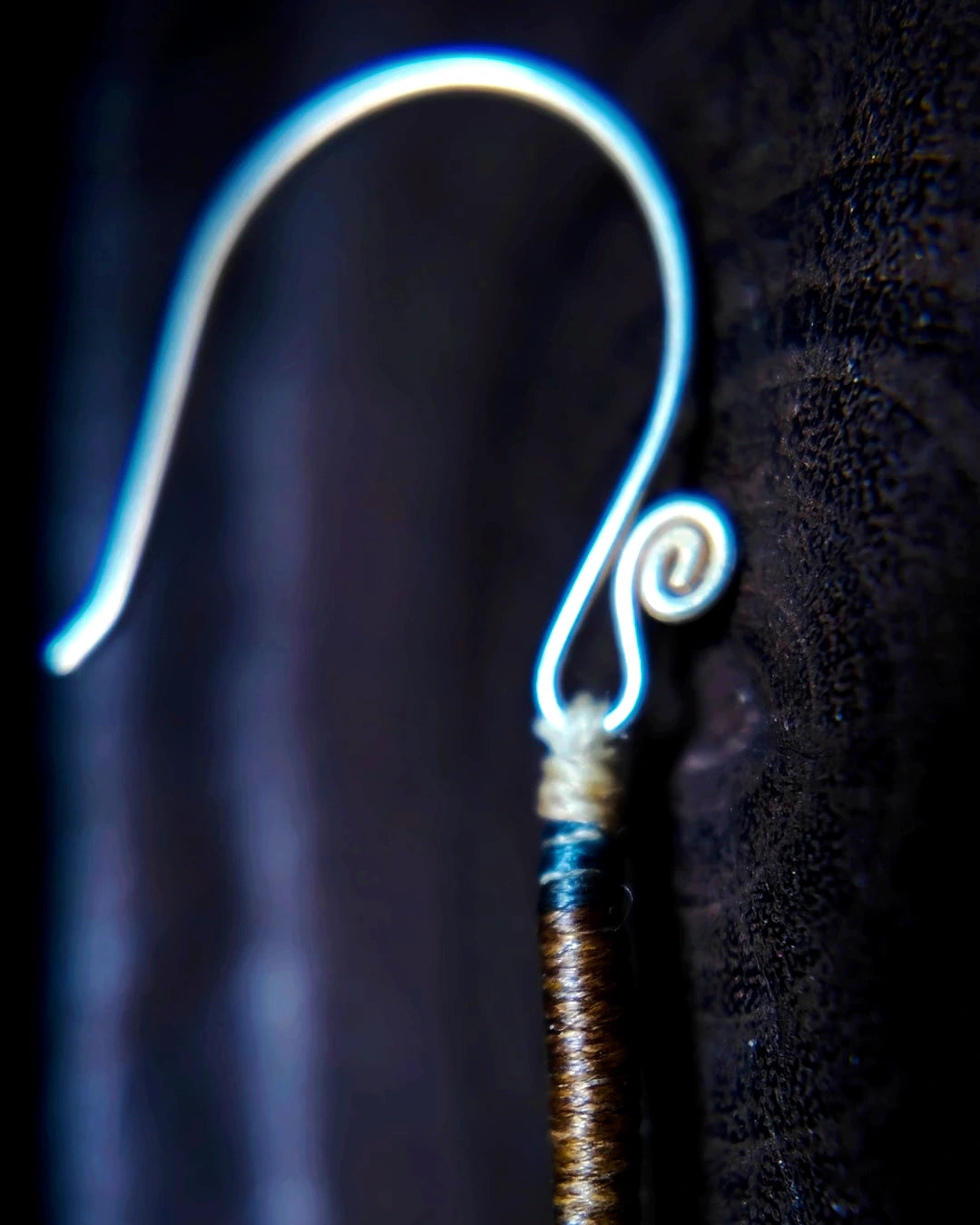 Macro detail of the waxed-thread construction and silver-plated copper ear hook