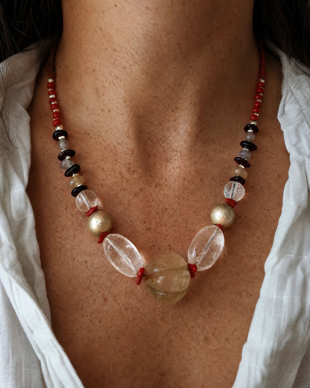 The Emberline #47 quartz and garnet necklace worn with a white open neckline