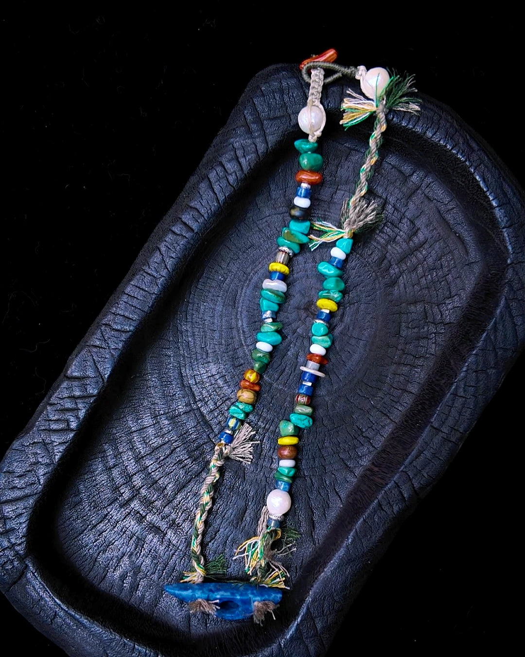 Full view of The Gatherer #37 carved lapis convertible choker and wrap bracelet on charred wood