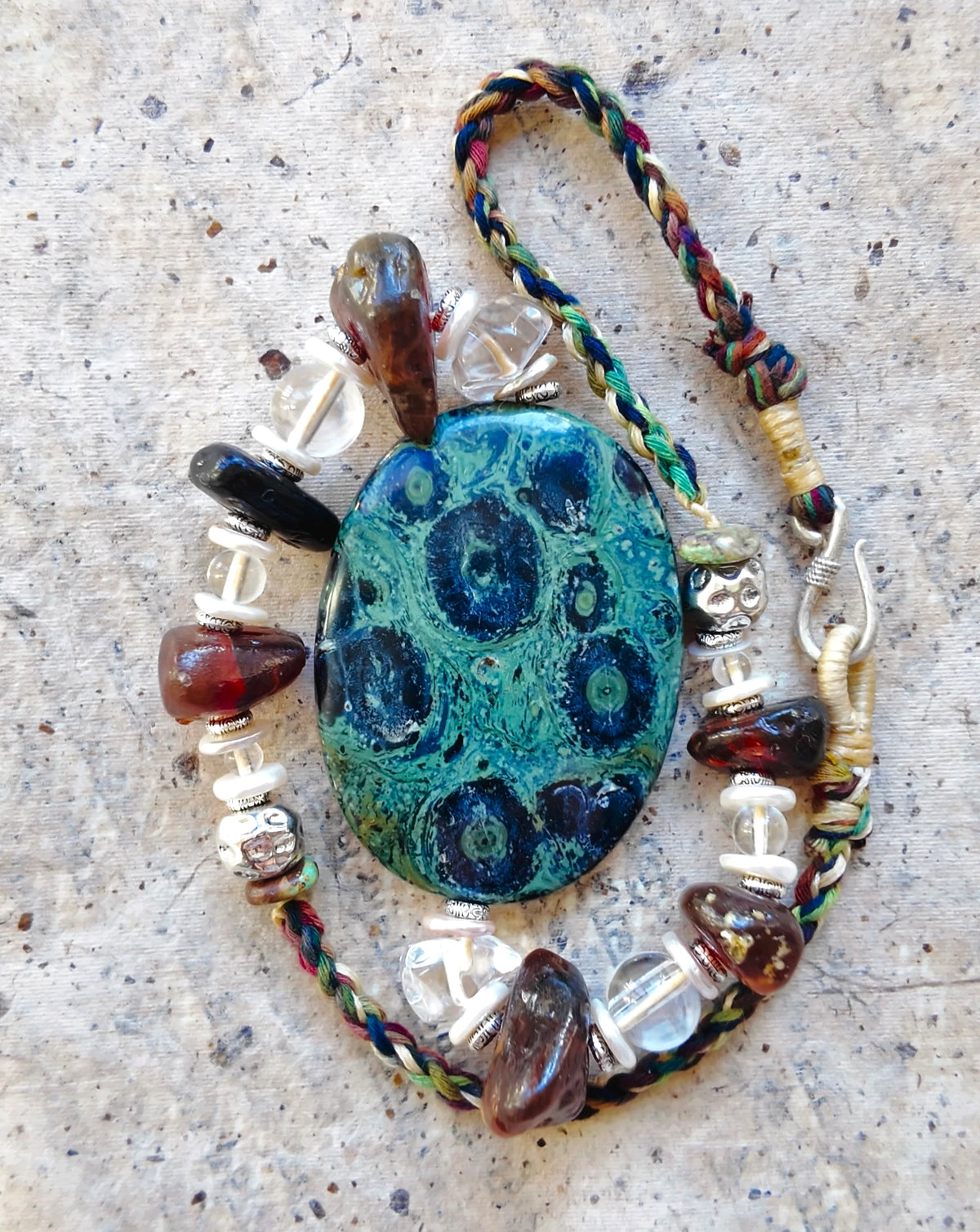 Coiled necklace showing the patterned green stone, multicoloured cord and clasp
