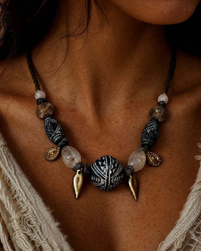 The Inkweave #59: Necklace worn with an open pale shirt, showing the carved clay focal and leaf drops