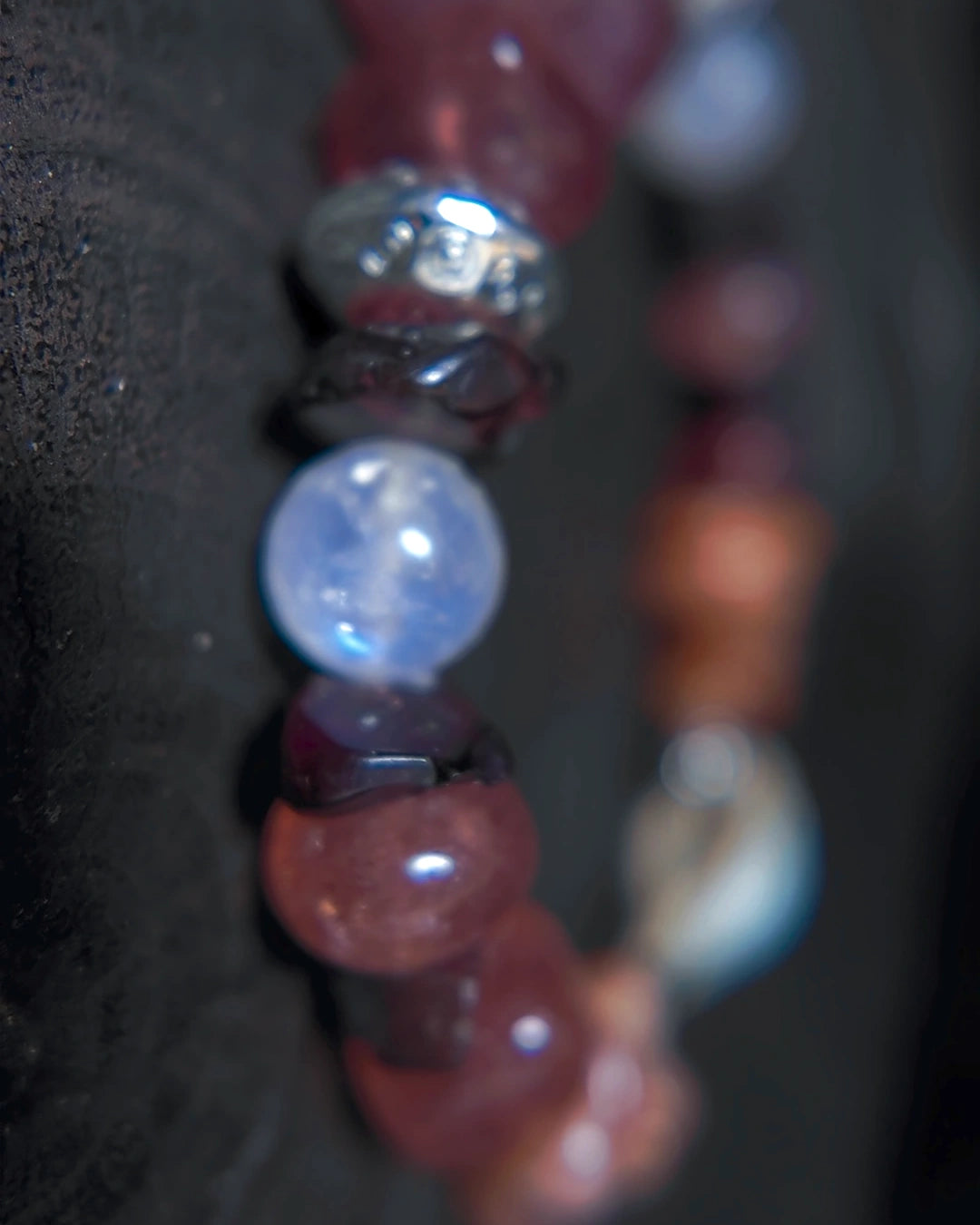 Macro detail of blue moonstone bead with garnet and antiqued metal accent