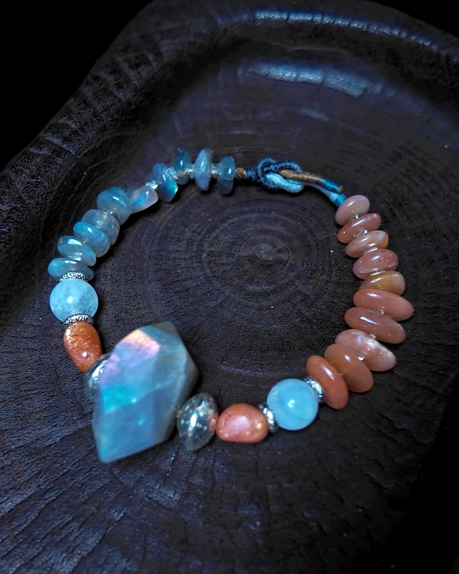 Full view of The Lucent #35 labradorite, sunstone and blue moonstone bracelet on dark wood