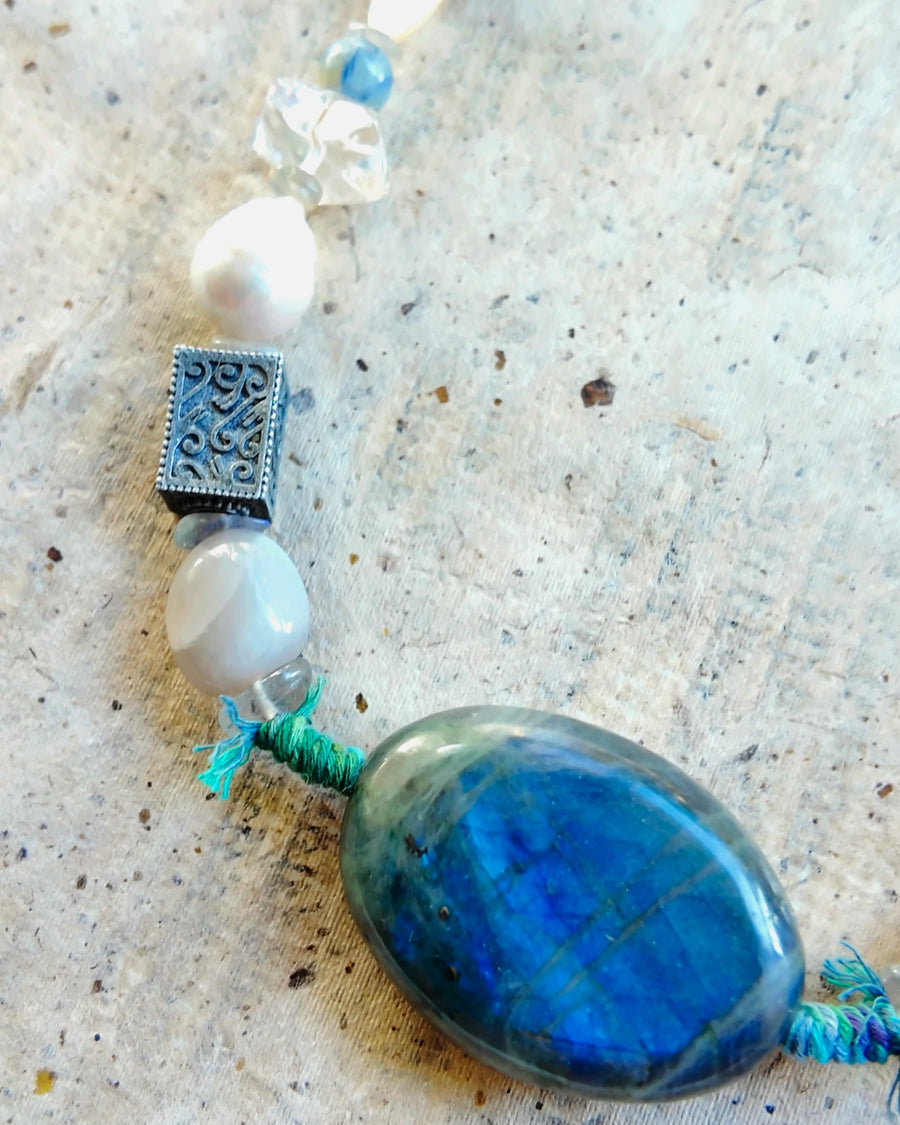 Labradorite, moonstone, engraved metal bead, baroque pearl, clear quartz and kyanite along the strand