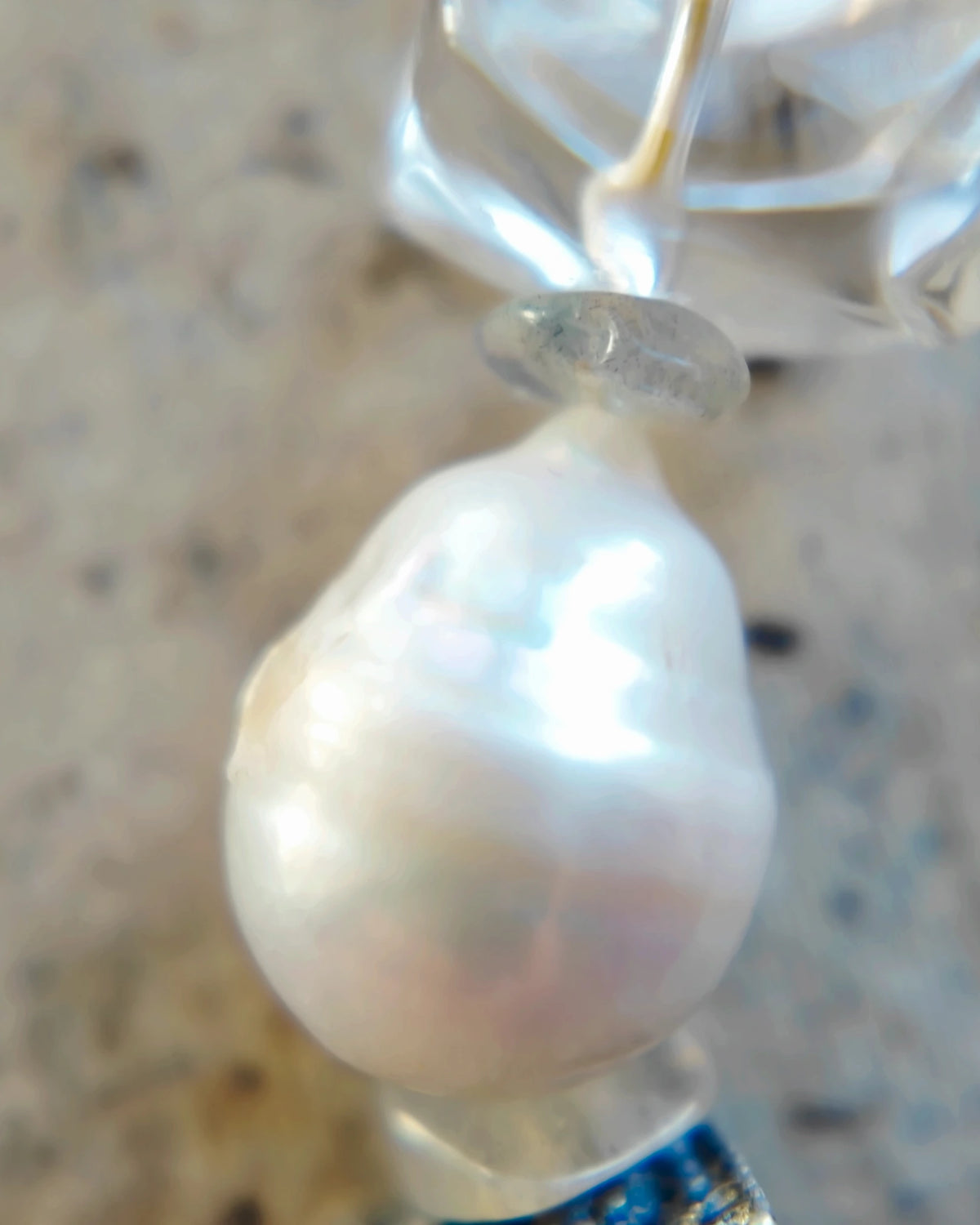 Irregular white baroque pearl beside a labradorite chip spacer